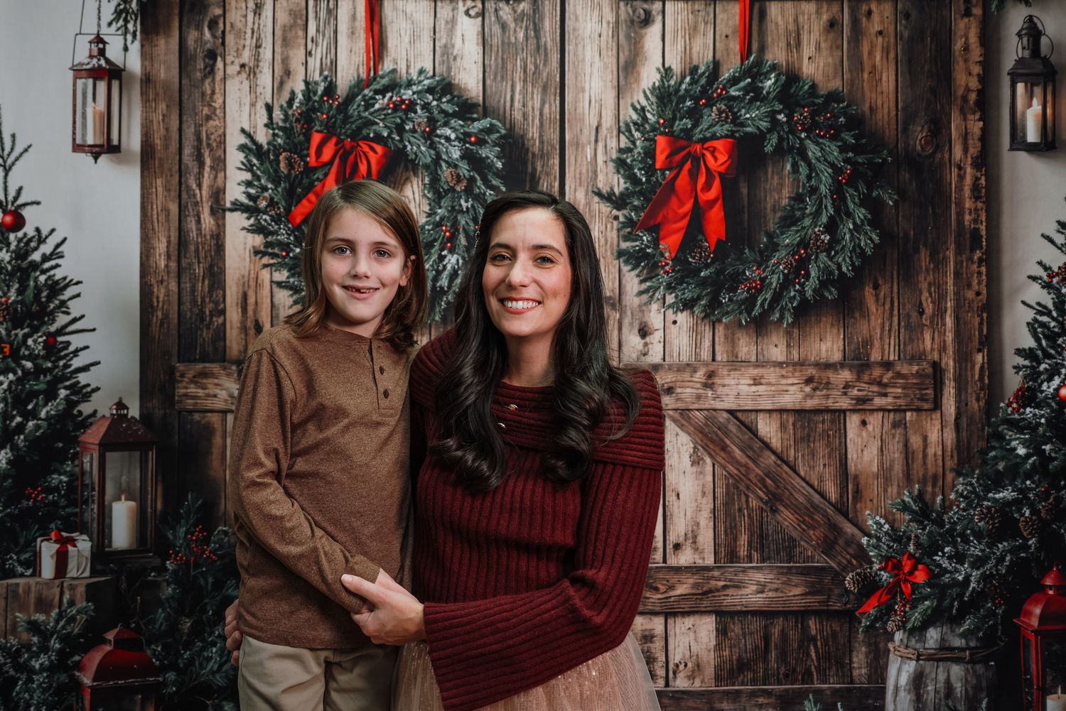 Rustic wooden door decorated with Christmas wreaths and red bows in a festive holiday setting.