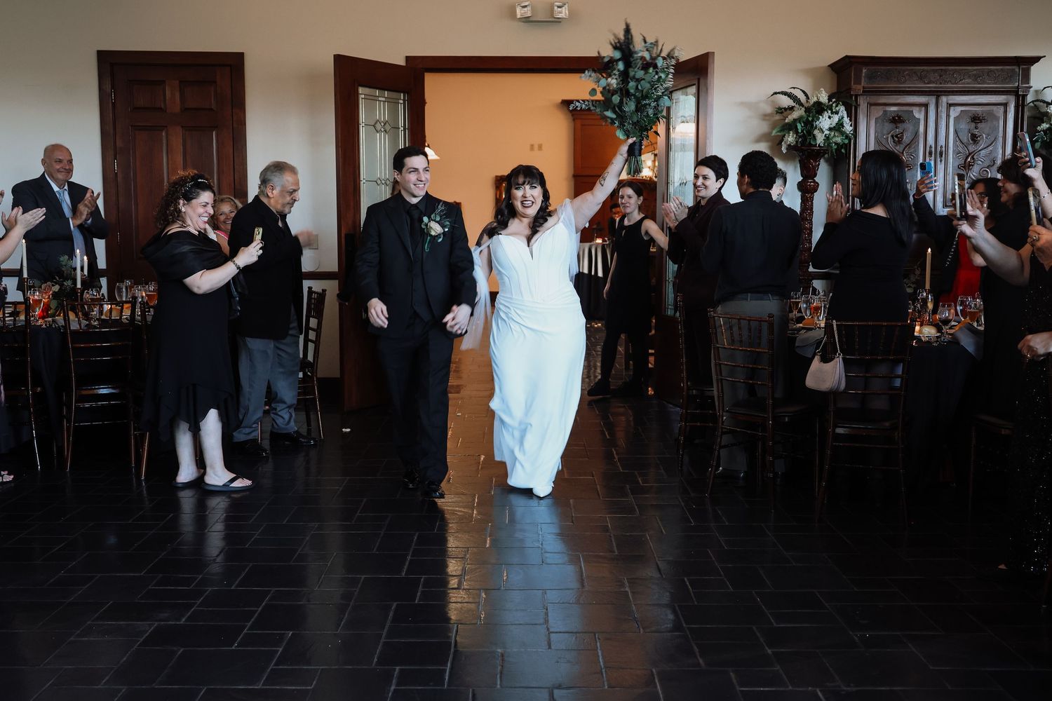 Wedding guests dance and celebrate together on a dark dance floor during an evening reception.