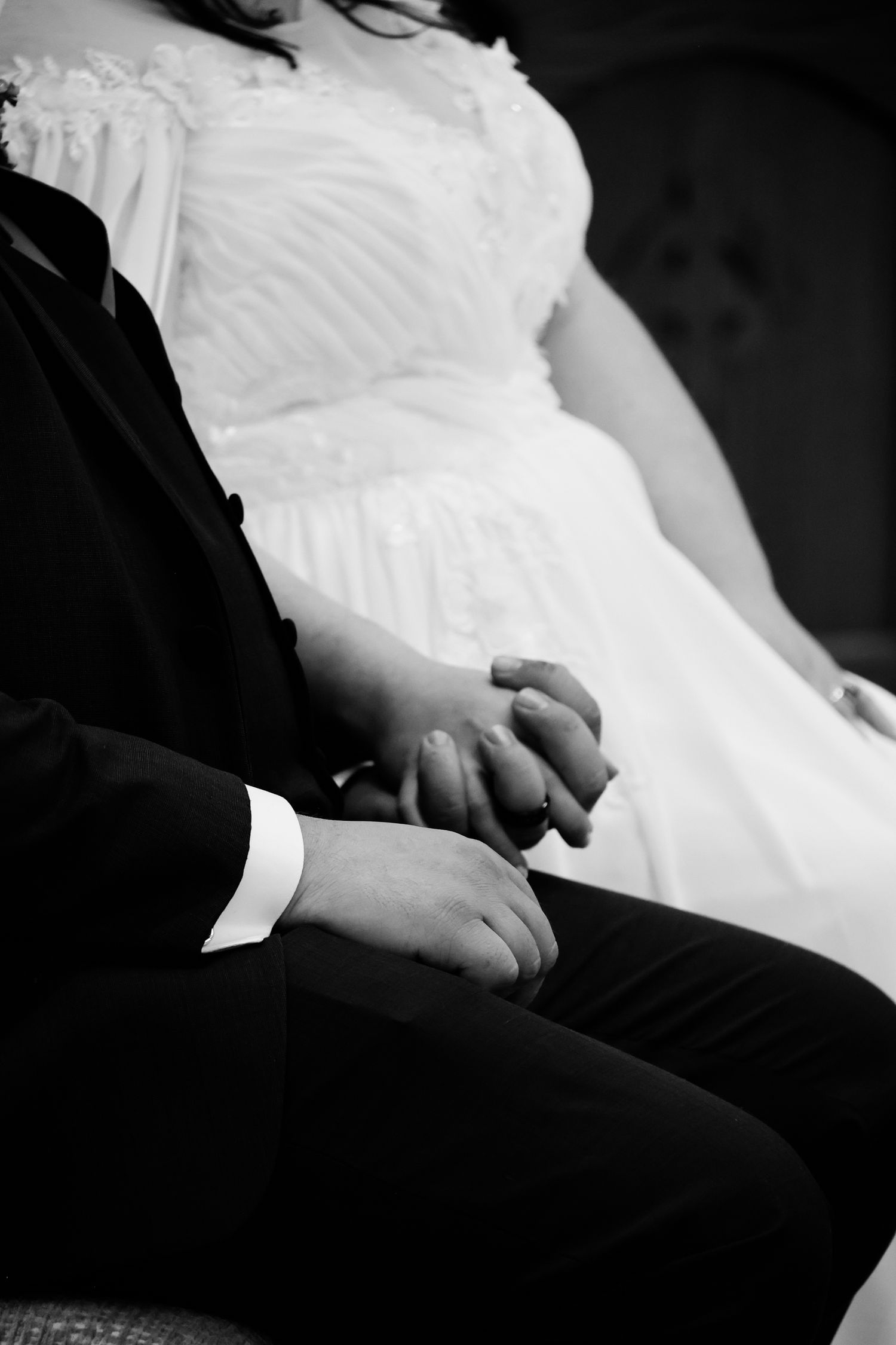 Black and white close-up of a bride and groom sitting together, showing their formal wedding attire.