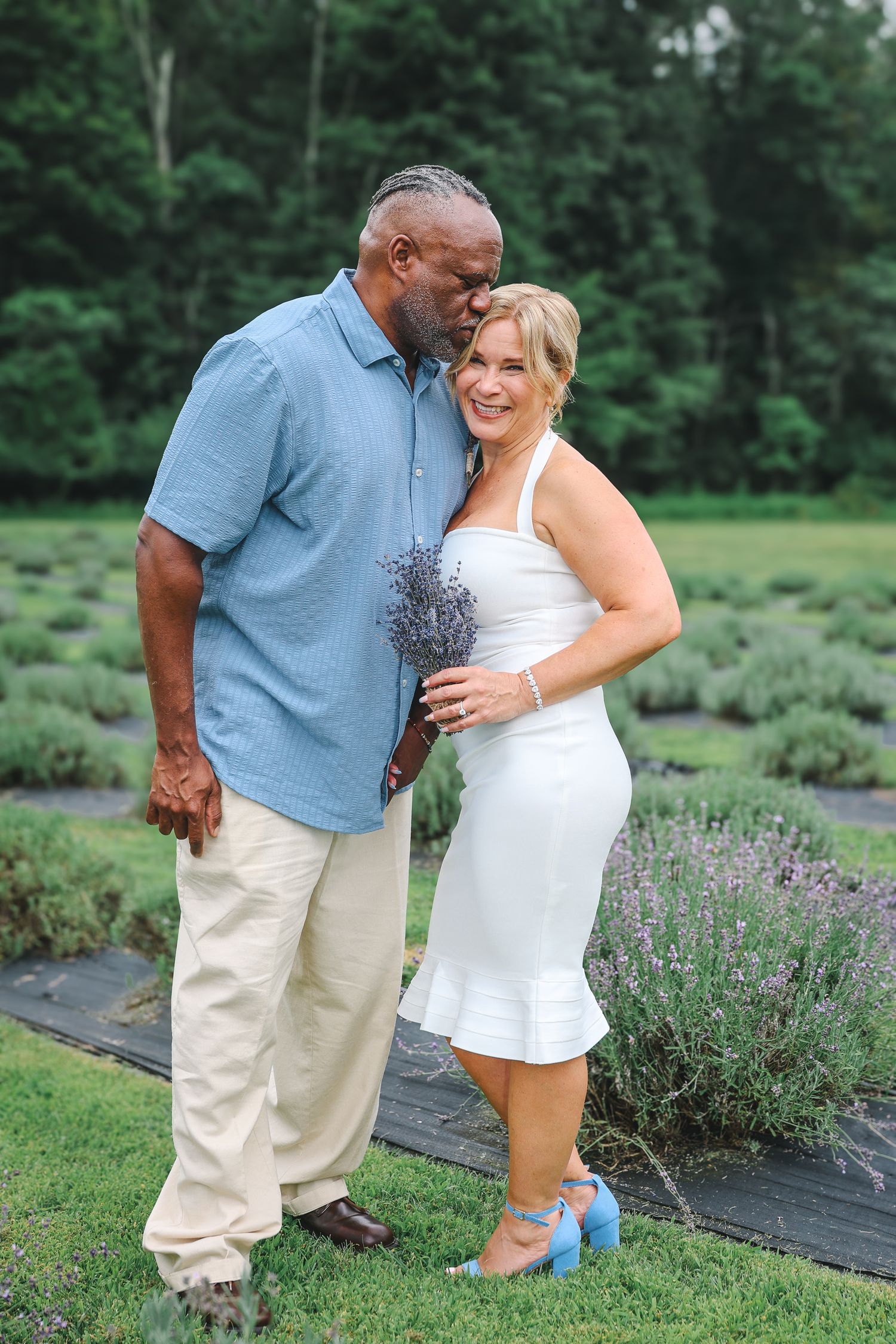 A couple embraces in a lavender garden during a summer photo session, creating romantic outdoor portraits.