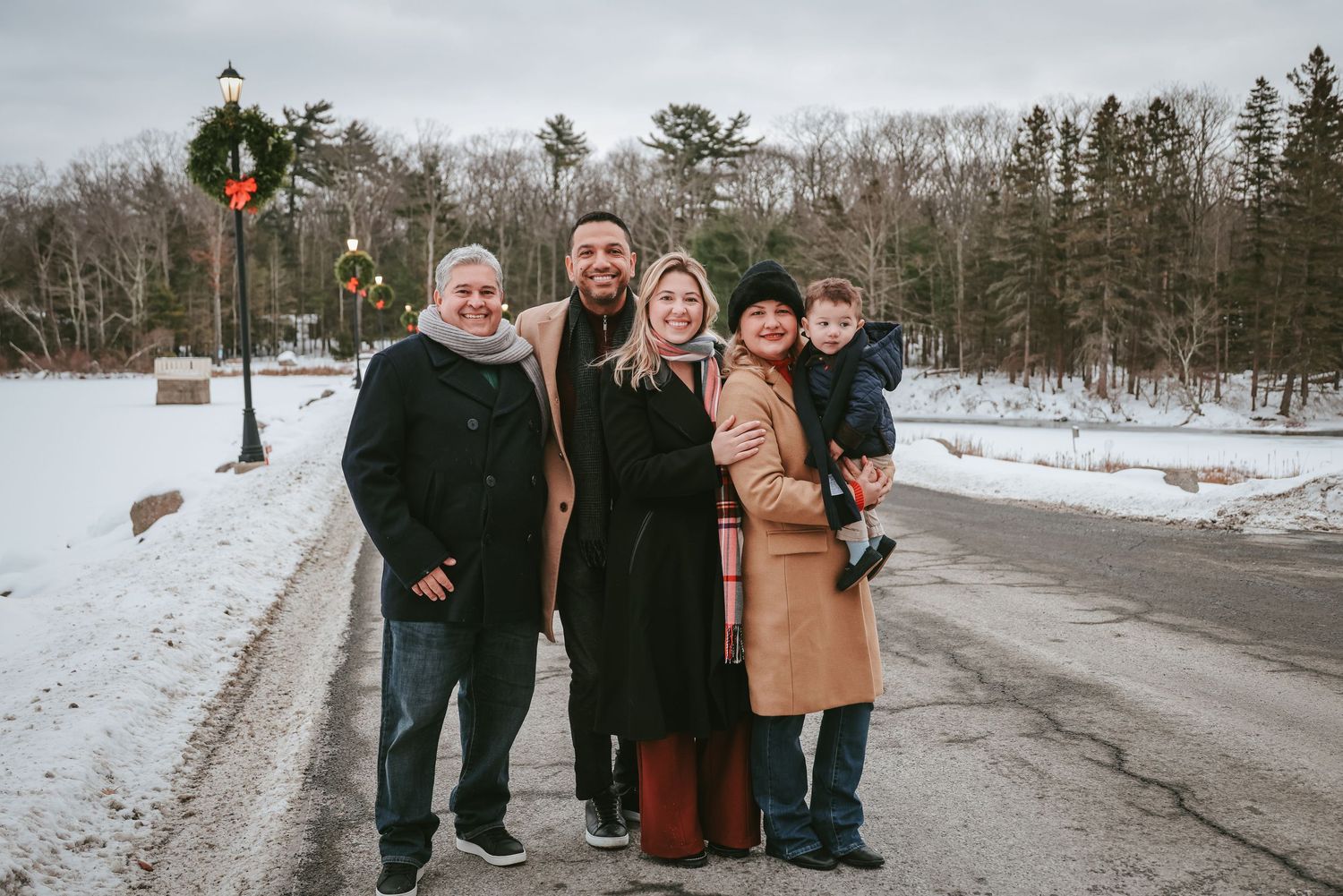 A group of people walking together on a snowy winter path through a wooded area.