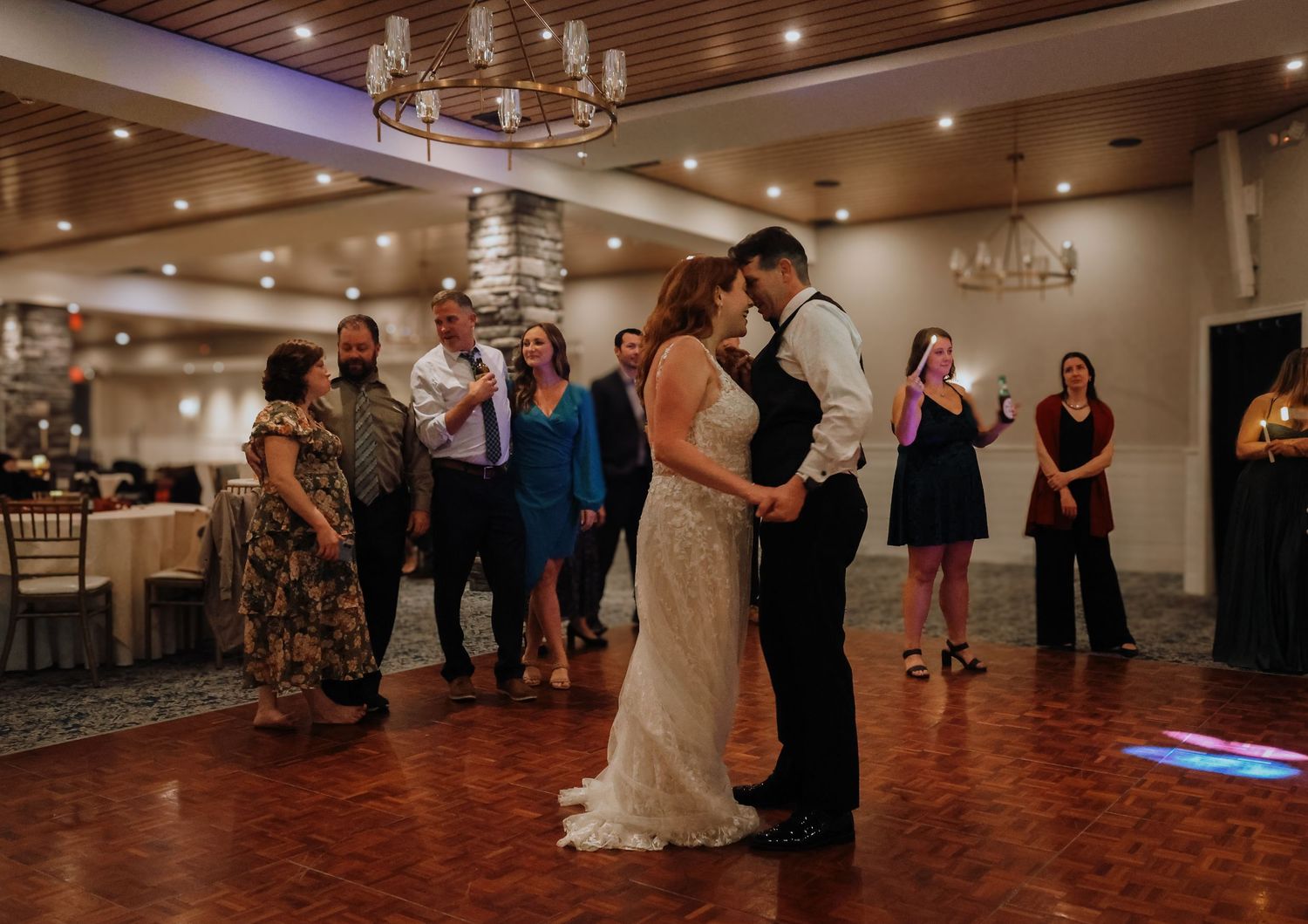 Wedding reception dance floor scene with couples dancing under warm lighting.