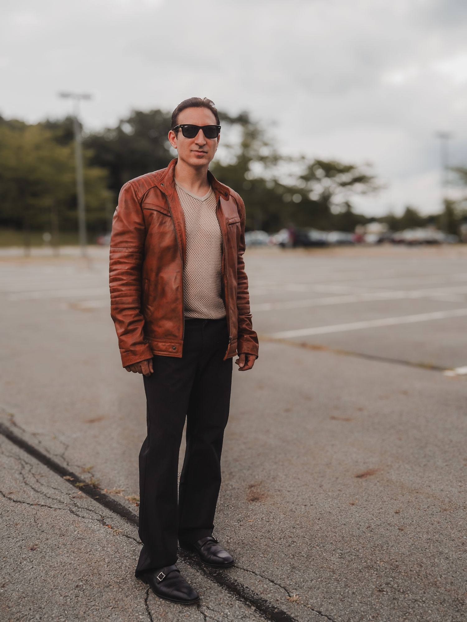 A person wearing a brown leather jacket and black pants walks on a paved surface in a series of motion shots.