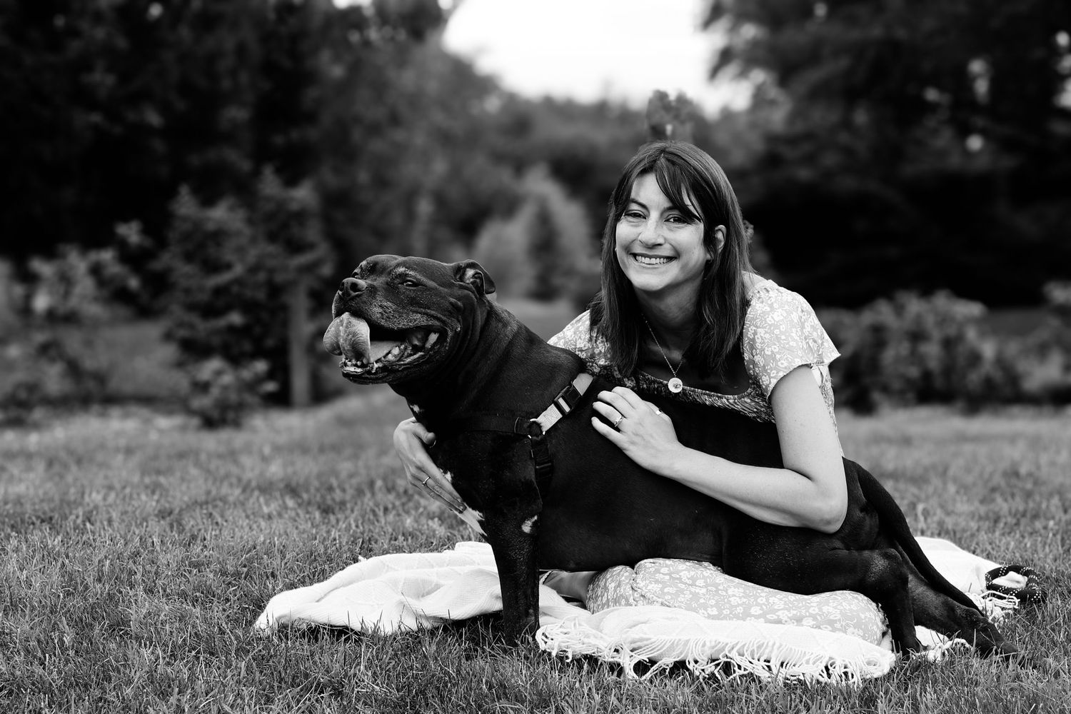 A series of black and white photographs showing playful moments between a person and their black Labrador dog outdoors.