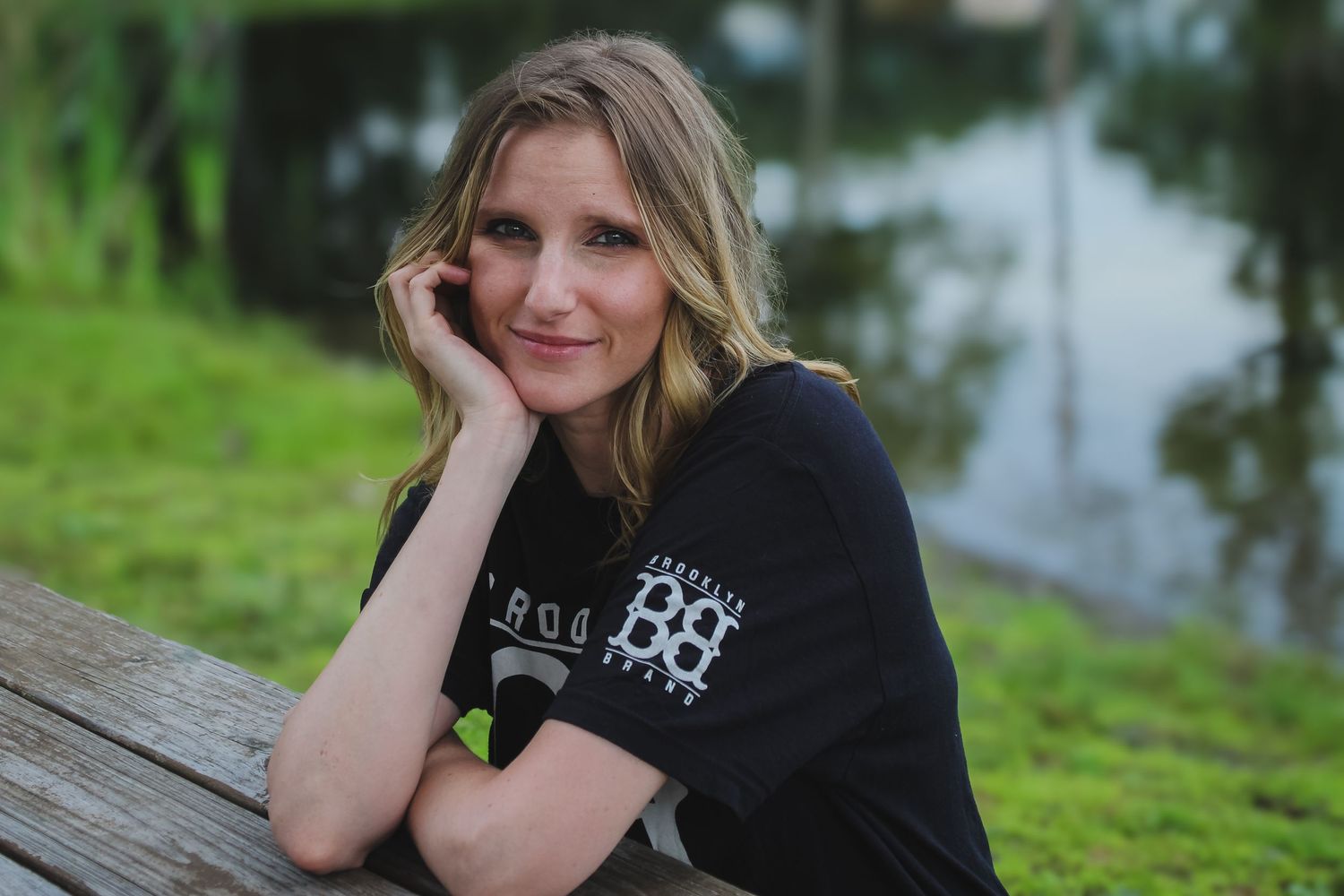 A series of five outdoor portrait photos showing someone in a black shirt sitting on a wooden bench in a natural setting.