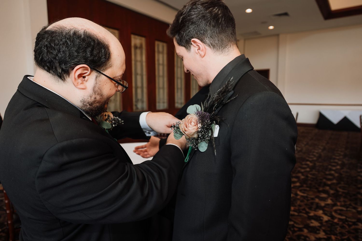 Groomsmen helping adjust boutonnieres and formal attire before ceremony.
