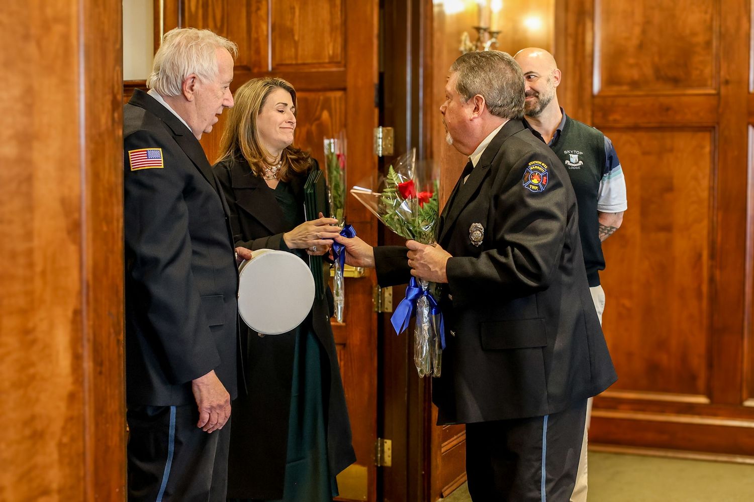 People gather in a wood-paneled room with warm lighting during what appears to be a formal event or ceremony.