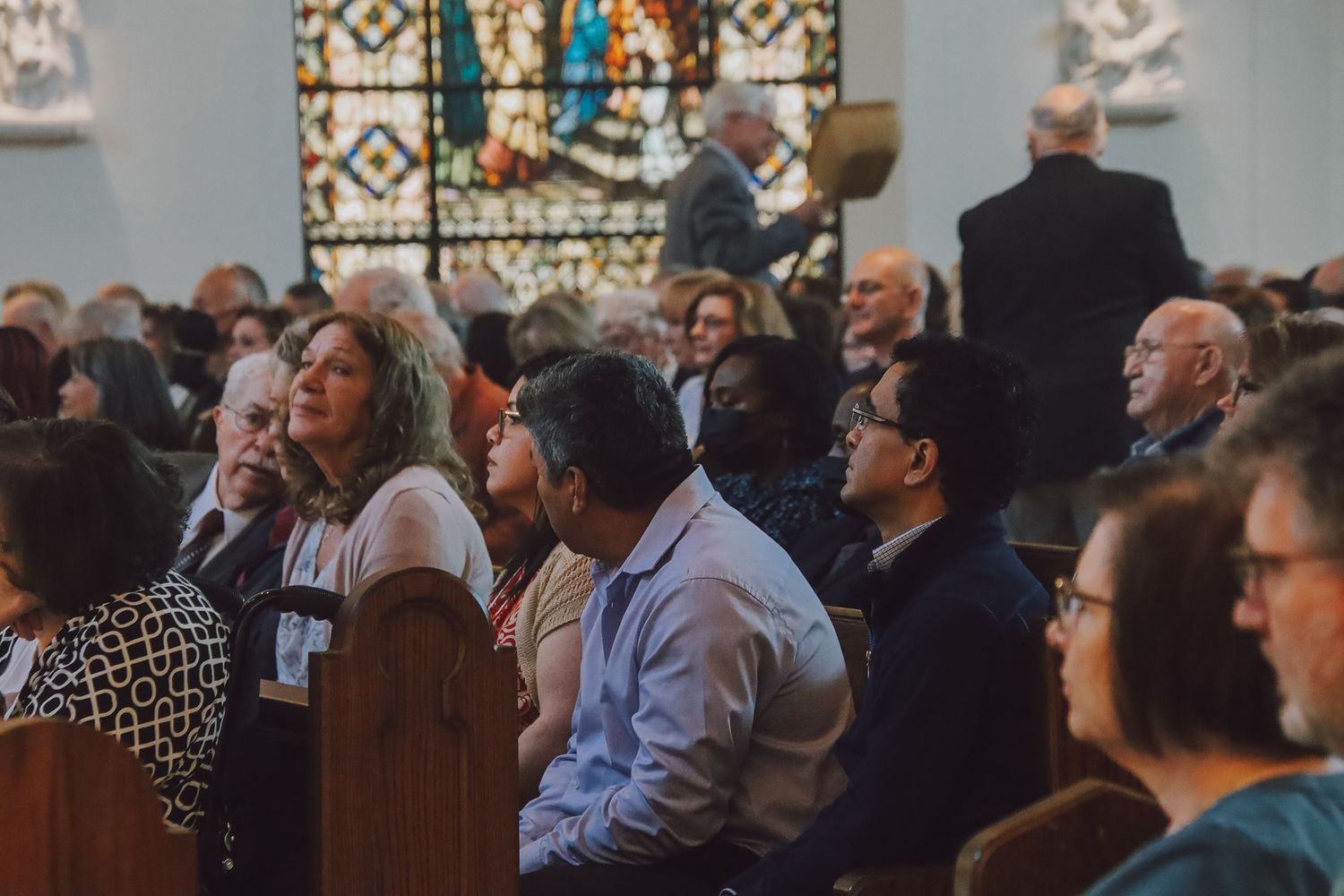 A diverse group of people sit in rows at what appears to be a conference or meeting venue.