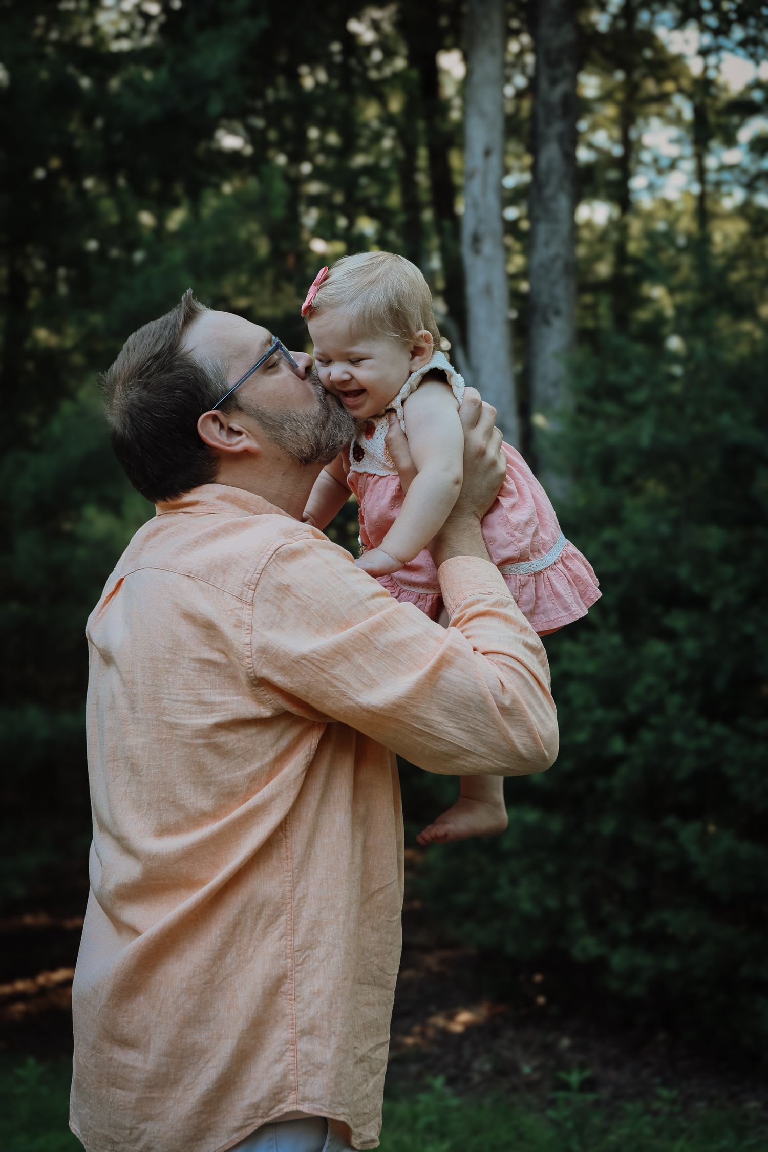A tender moment between parent and child playing together in a wooded outdoor setting during golden hour.