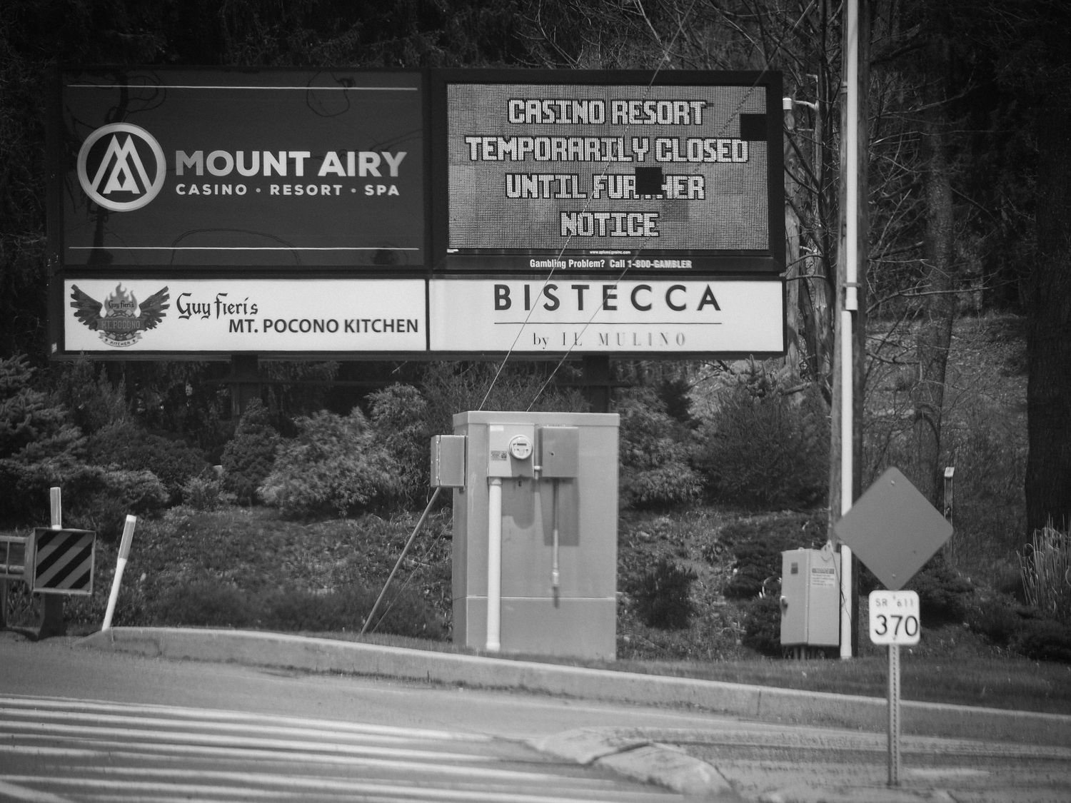 Black and white photo of a storefront entrance with Mount Airy and Bistecca signage on a concrete wall.