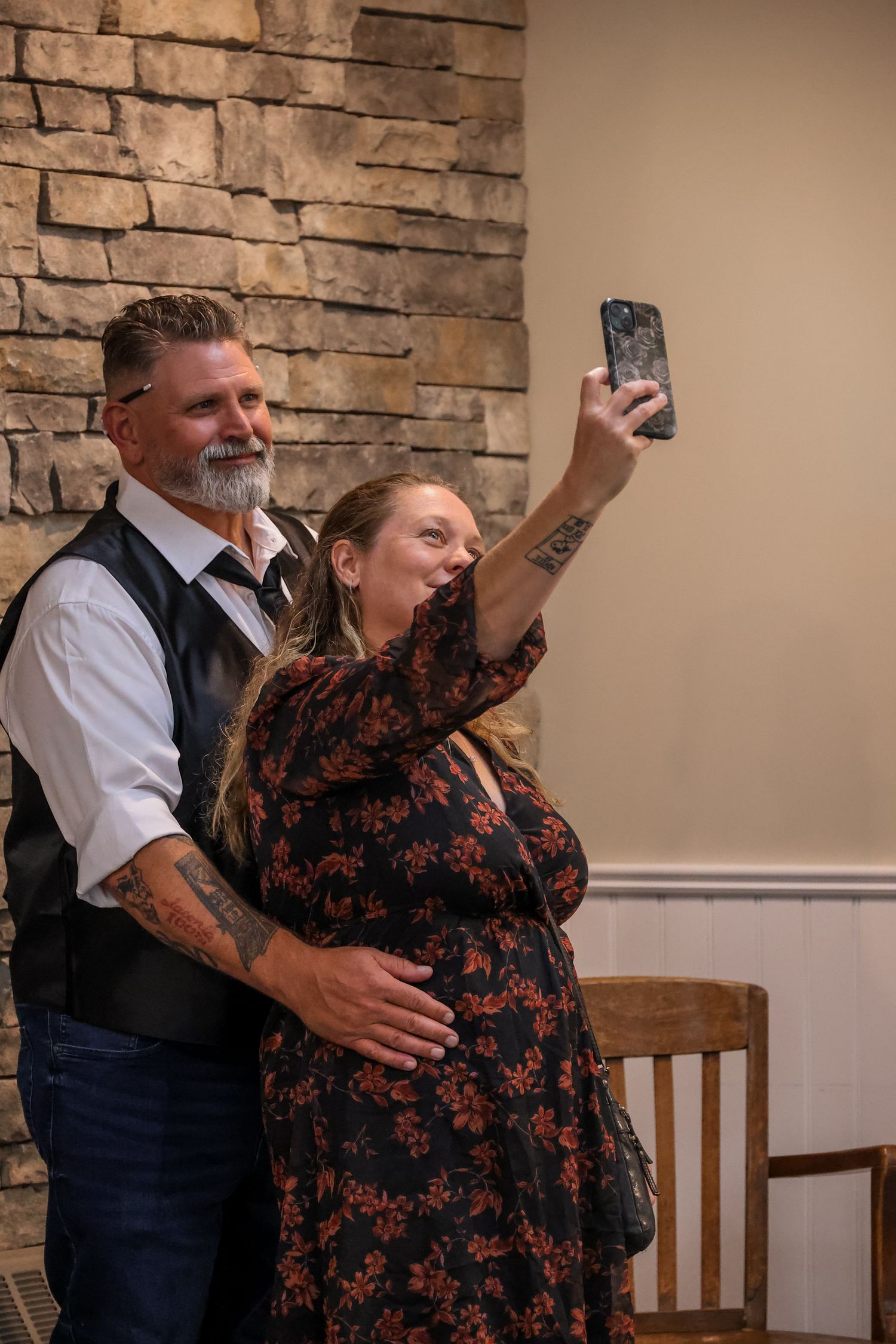 A couple shares a tender dance moment together in front of a stone wall in an indoor setting.