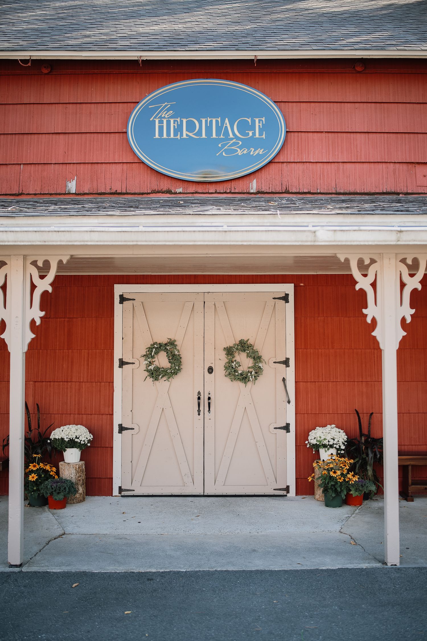 Red barn exterior with white barn doors and wreaths showcases Heritage sign and rustic farmhouse charm.