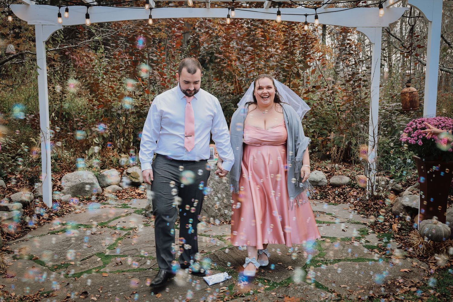 A couple in matching pink and grey outfits pose together in a garden setting during a photo session.