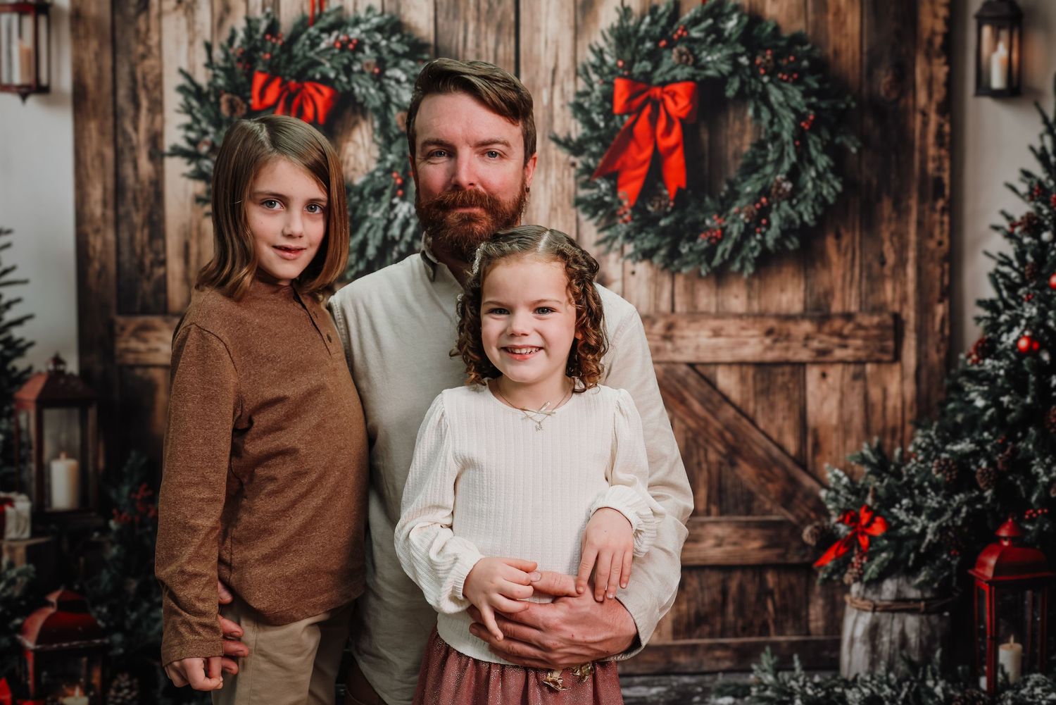 A rustic holiday photo session featuring a wooden backdrop, festive greenery and red bows for Christmas portraits.