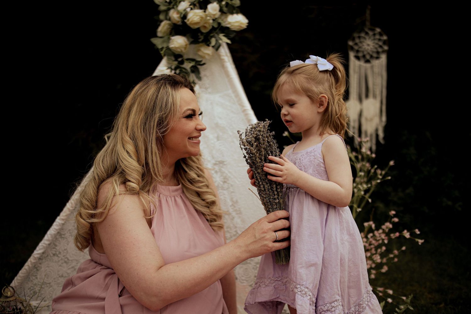 Bridesmaids in pink dresses share joyful moments during an outdoor wedding celebration.