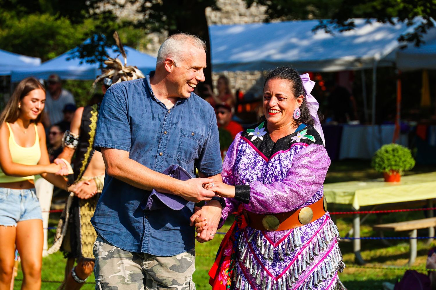 Couples dancing together outdoors in a park during a sunny summer day.