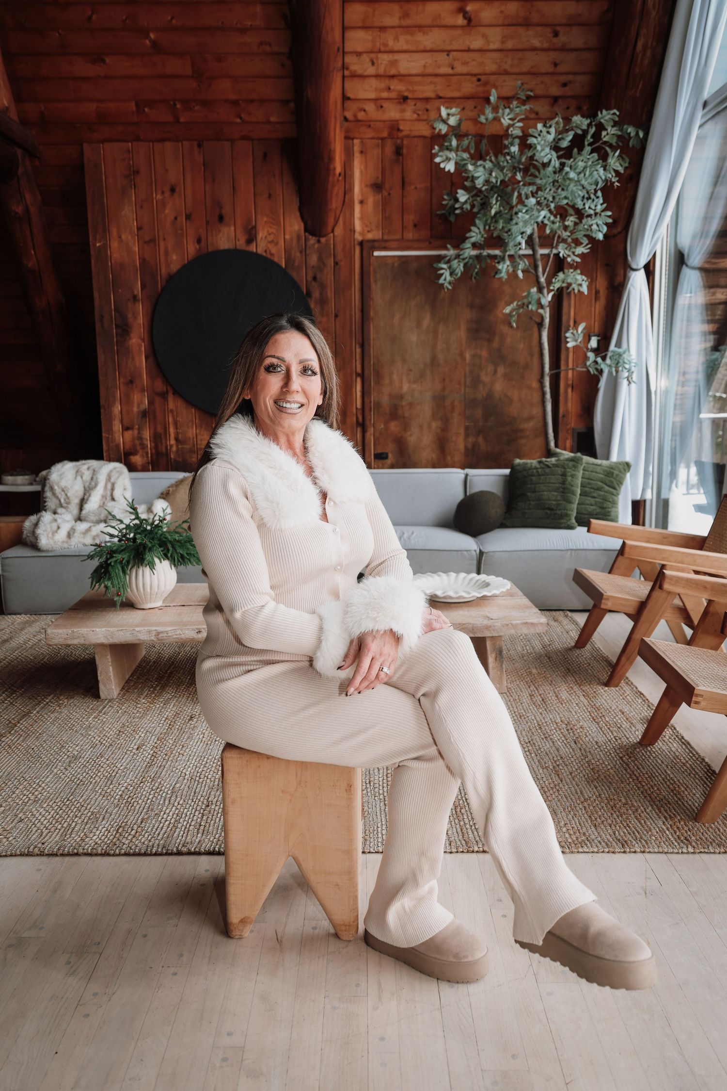 A cozy scene showing someone in a plush white sweater lounging on a wooden bench against rustic barn wood walls.