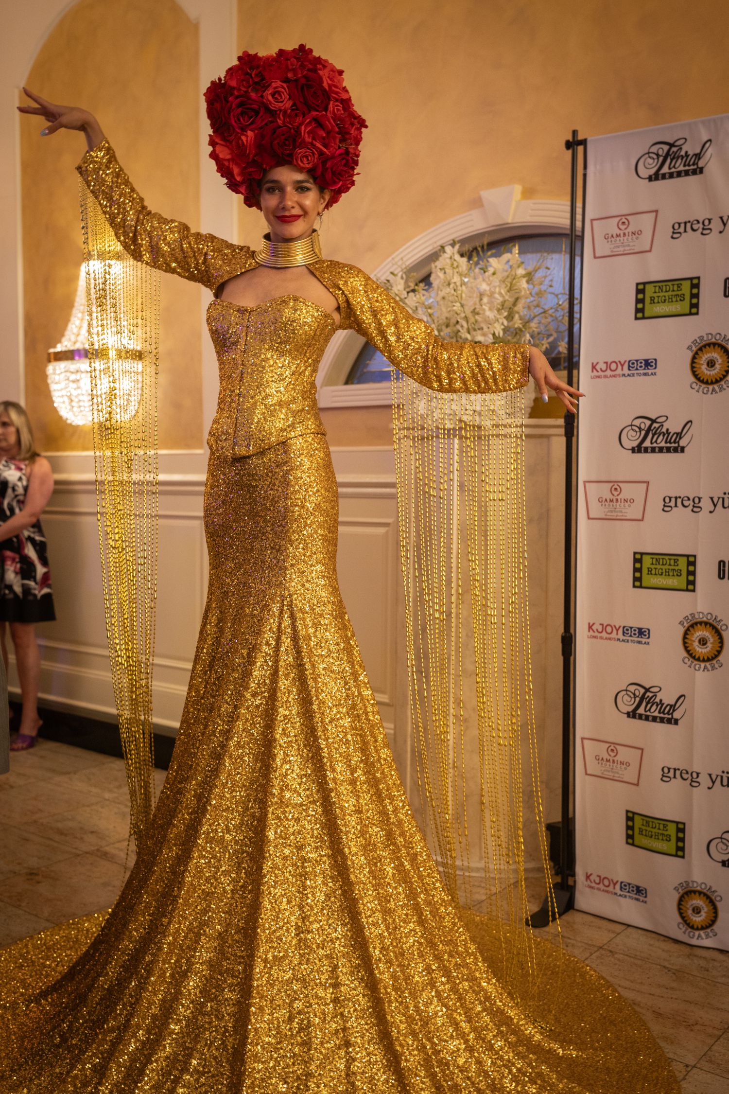 A stunning gold sequined ball gown with a dramatic silhouette displayed at an event with crystal chandeliers.