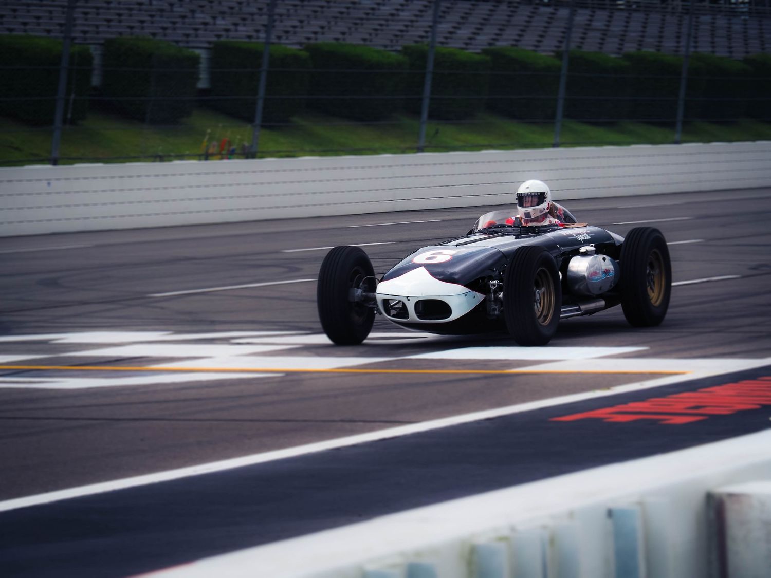 Formula One race cars speeding through a wet racetrack during a competitive motorsport event.