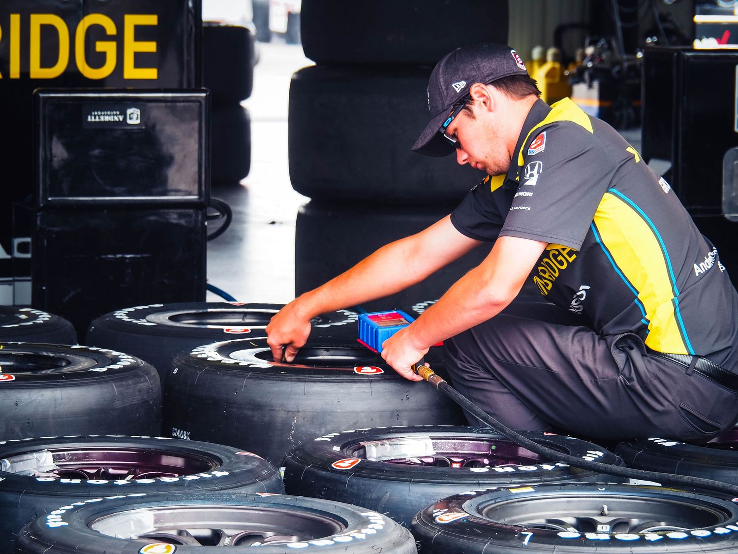 Mechanic in black uniform inspecting and working on a tire at an automotive service center.