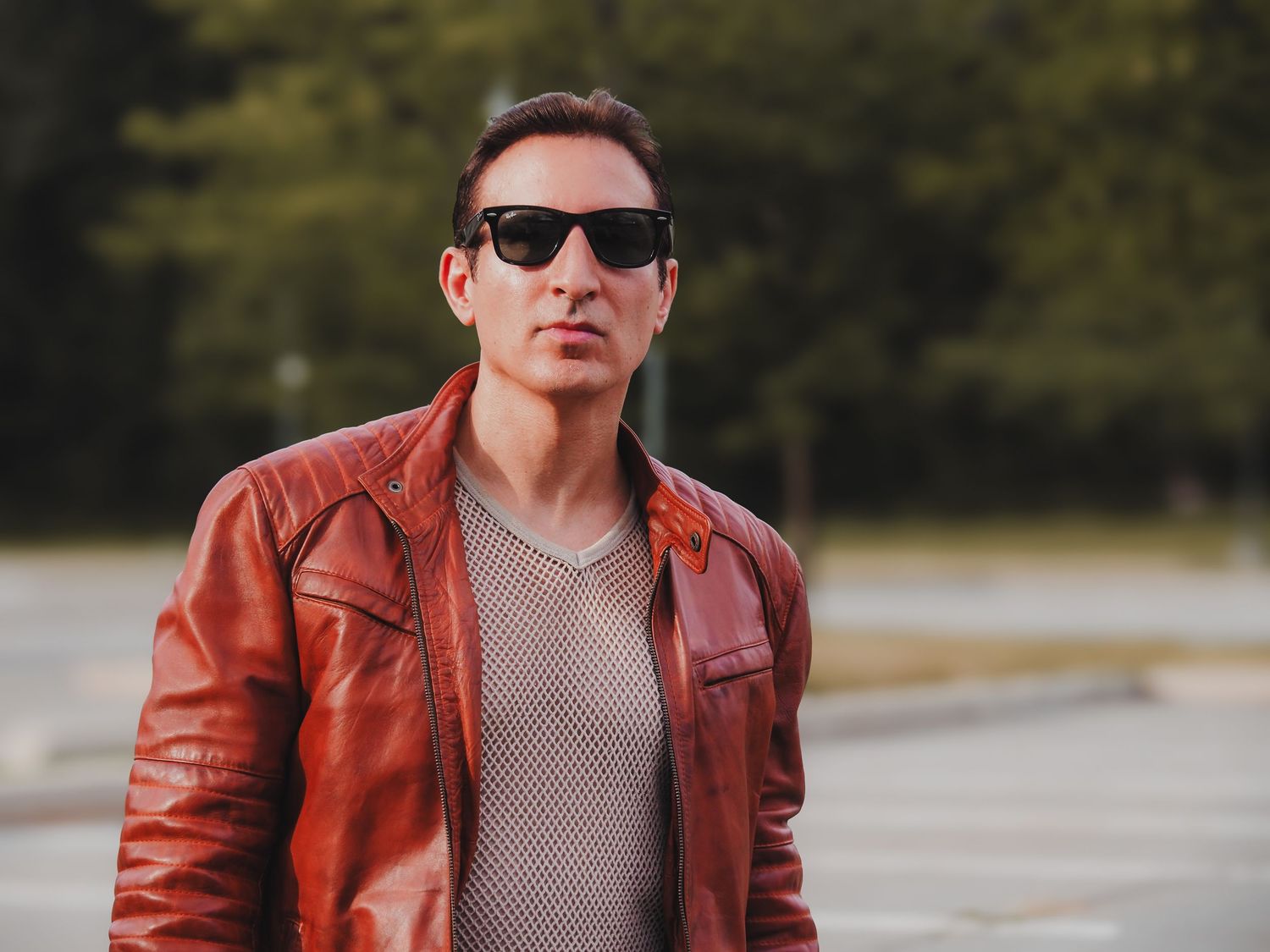 Person wearing sunglasses and a brown leather jacket poses in multiple shots outdoors.