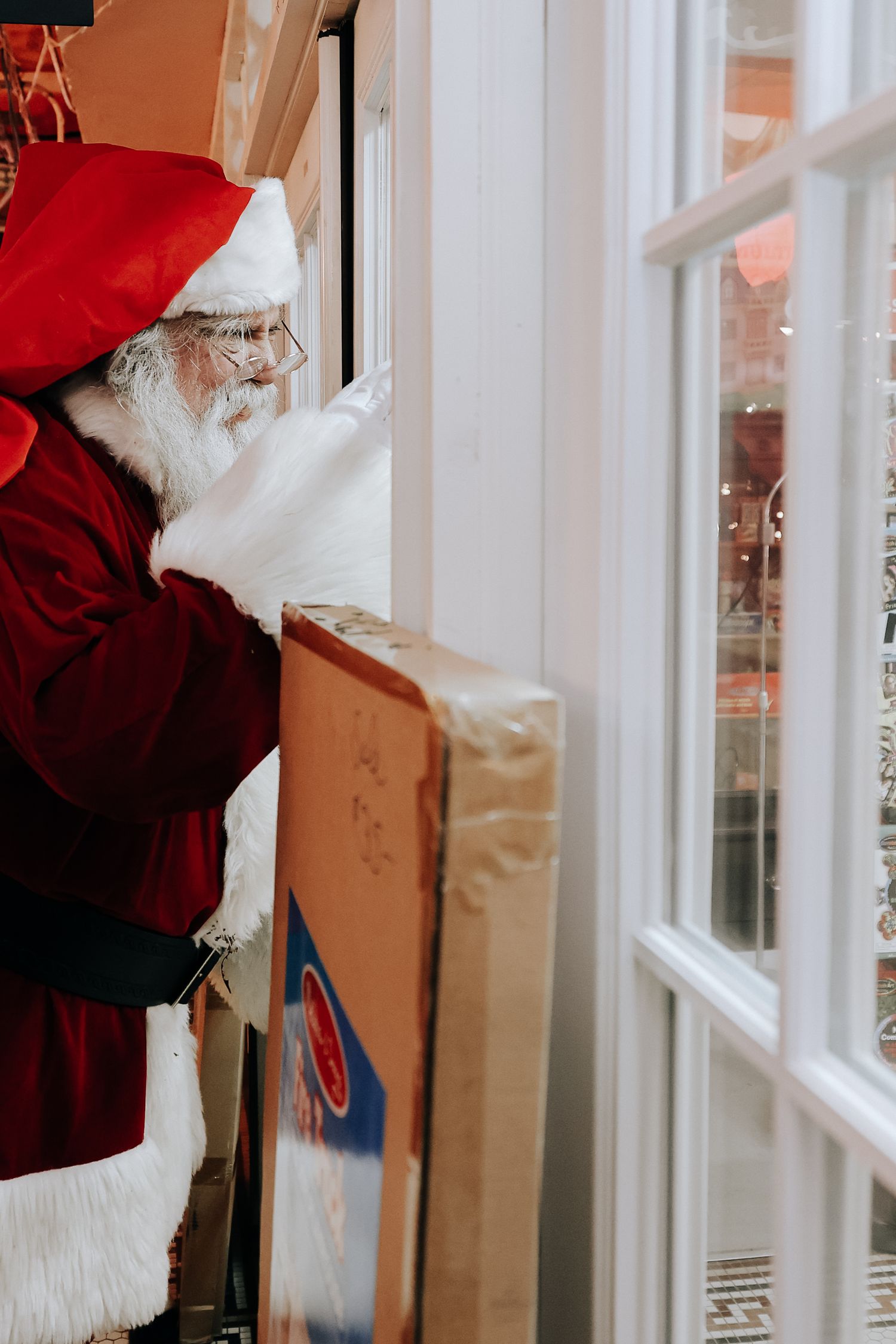 A person in a red Santa suit peers through a window during the holiday season.
