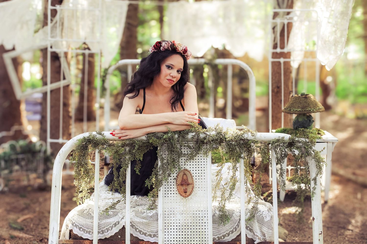Rustic outdoor wedding reception setup with white tablecloths, floral centerpieces and string lights in a wooded setting.