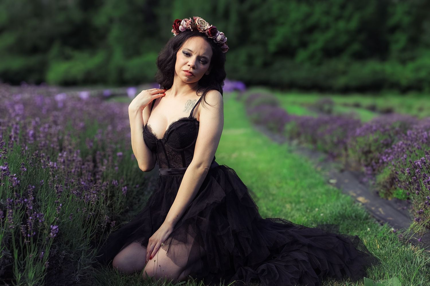 A person in a black dress poses gracefully among blooming purple lavender fields on a summer day.