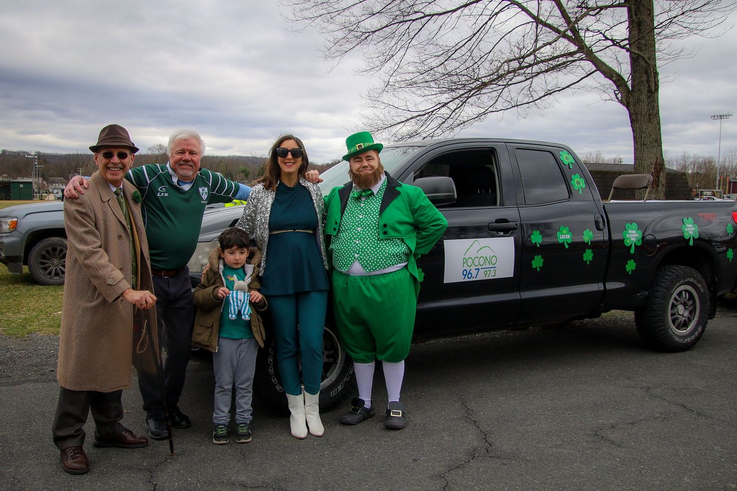 A series of five photos showing people gathered around a black stretch limousine decorated with green accents.