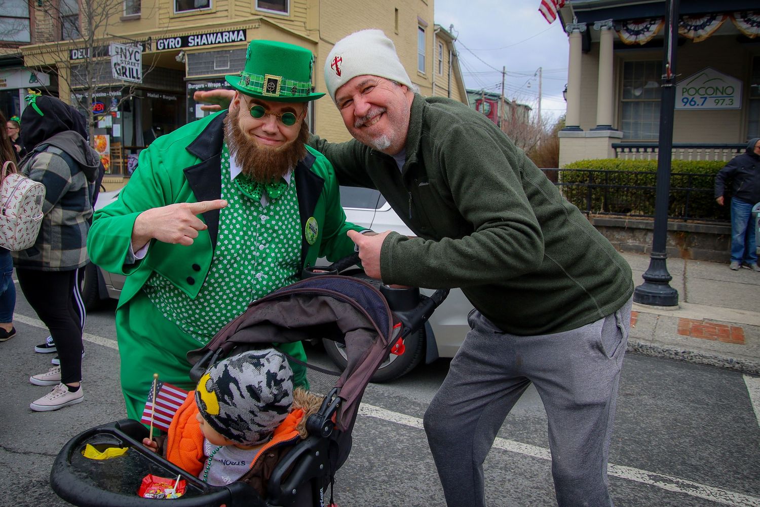 People wearing festive green clothing celebrate St Patrick's Day on a city street.