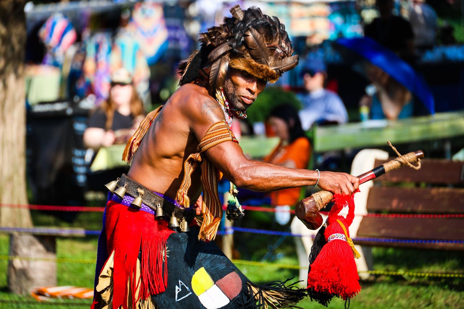 Traditional Native American dancers perform in vibrant red regalia during an outdoor cultural celebration.