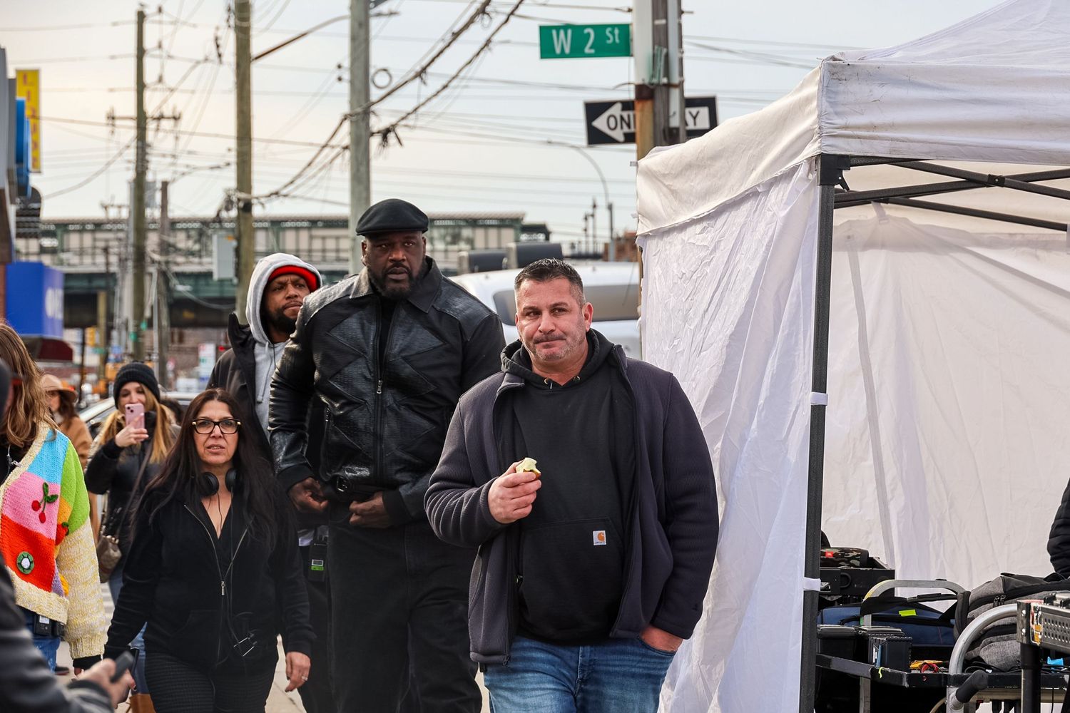 Outdoor winter market scene on a city street corner with shoppers and vendors near white tents.
