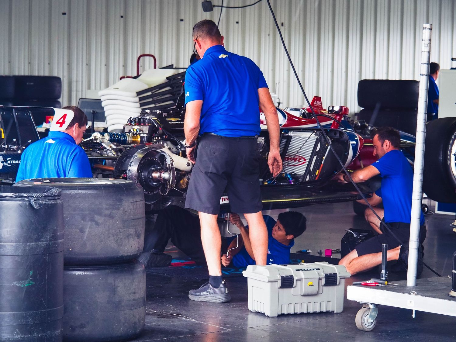 Mechanics working in an auto repair garage with multiple service bays and equipment visible.