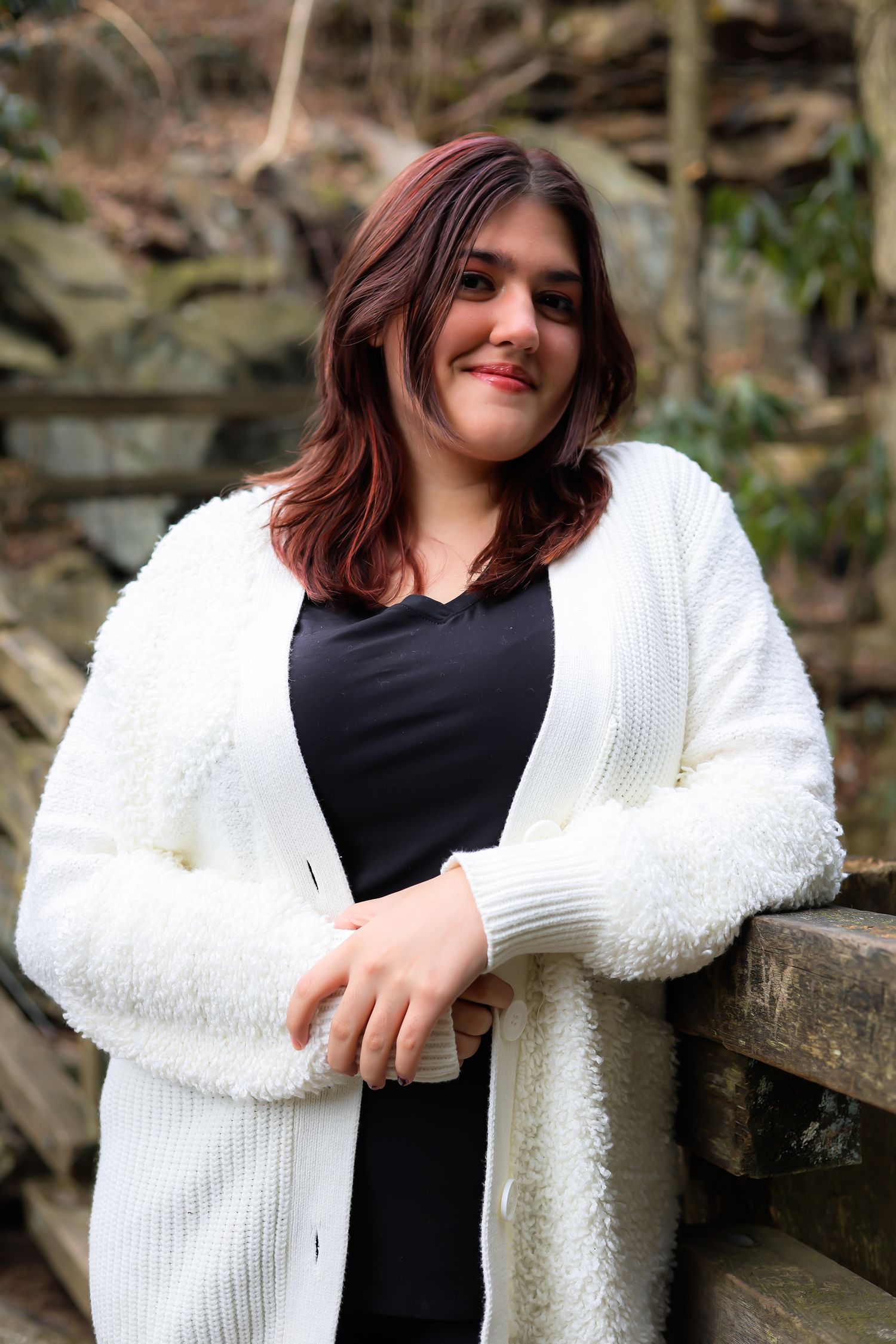 A series of photos showing someone wearing a black shirt and cozy white cardigan while posing outdoors near stone walls.