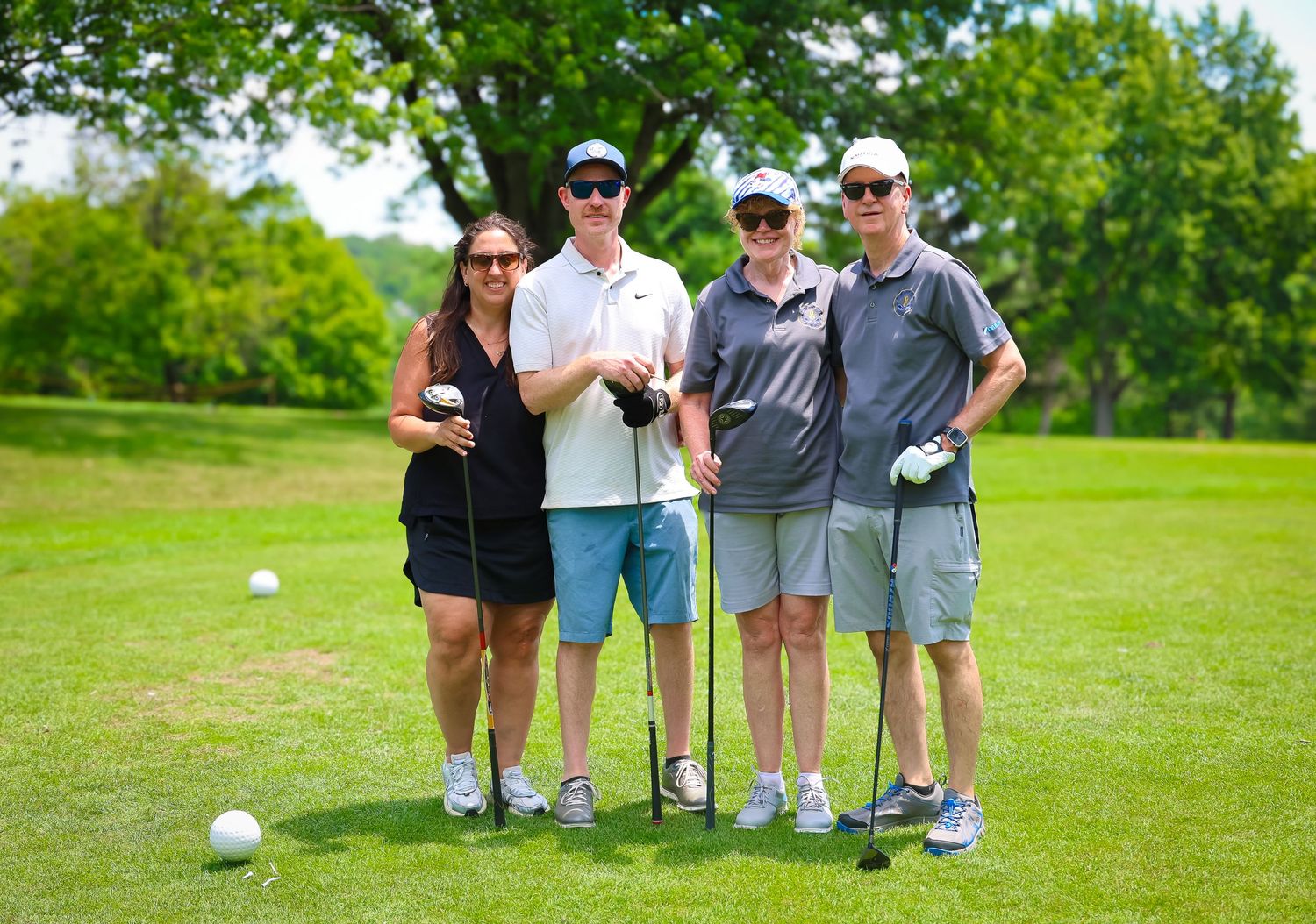 Golfers line up on a lush green course to practice their putting skills during a sunny day.