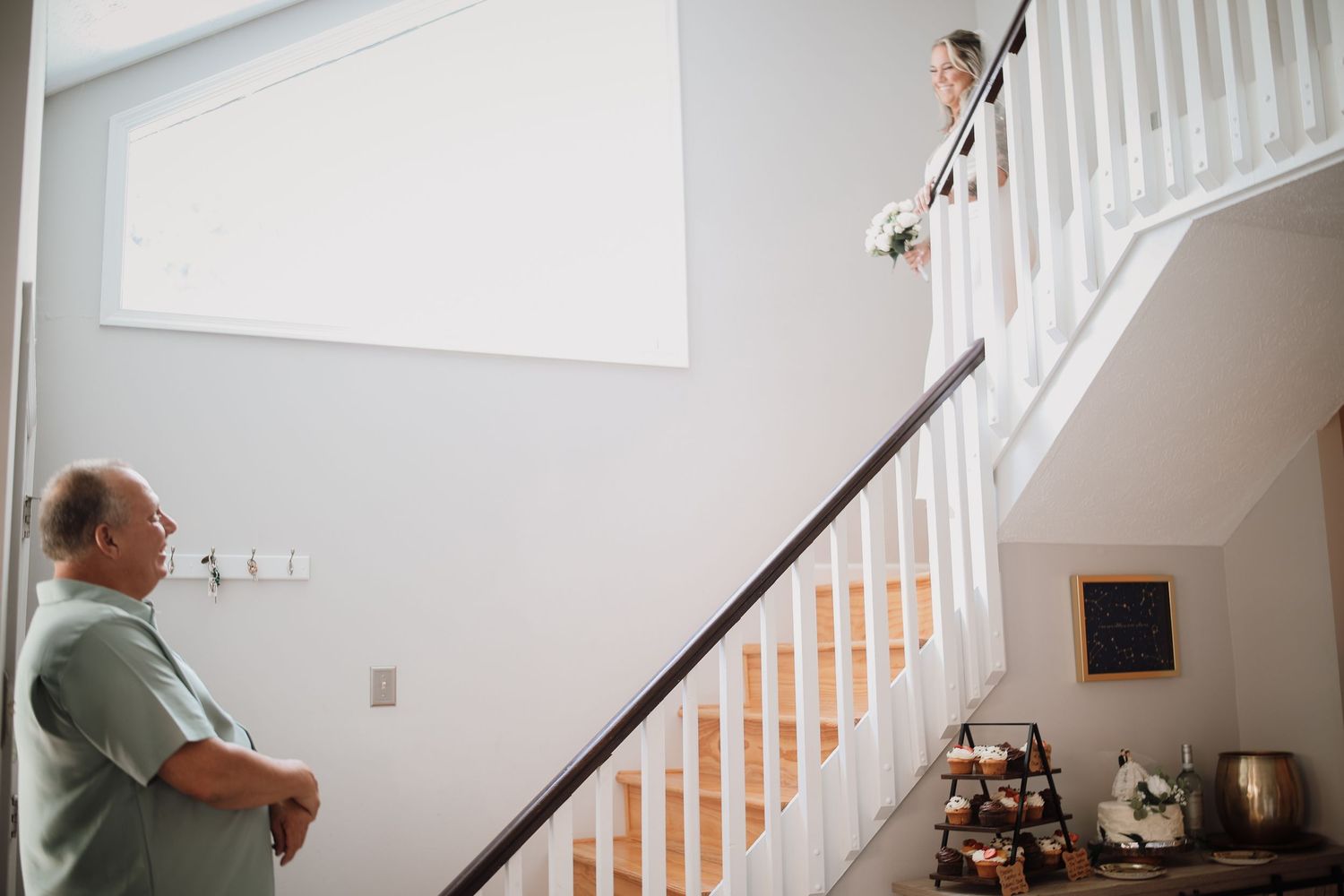 A person vacuums white carpeted stairs in a bright interior stairwell with natural lighting.