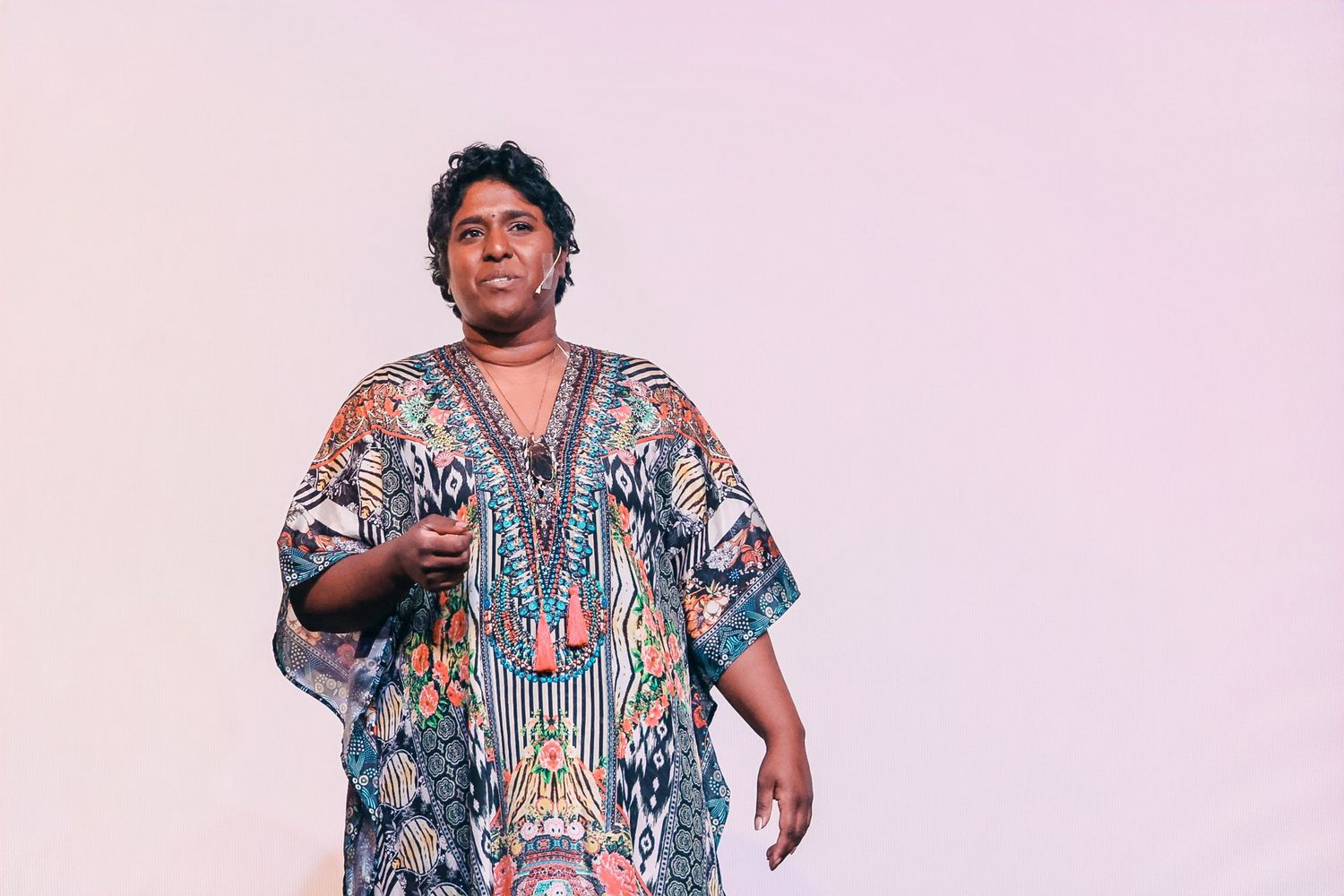Person wearing a colorful patterned kaftan dress standing against a light background.