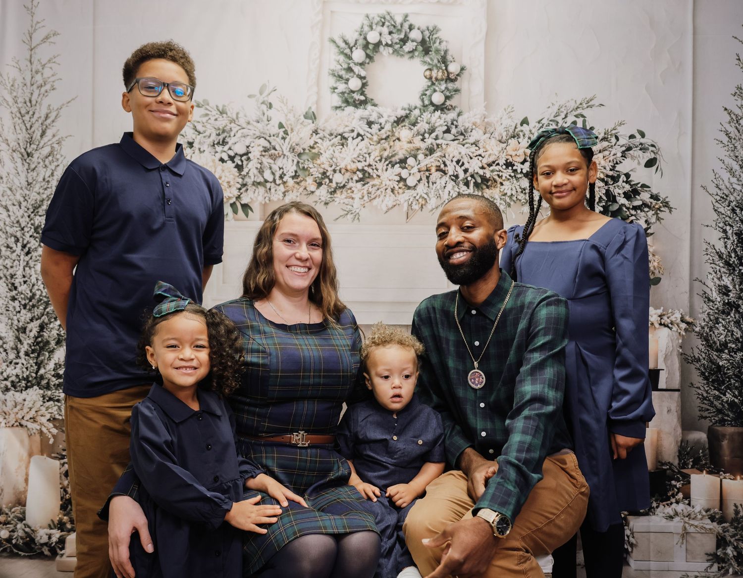 A multi-generational family poses together for a professional holiday portrait session in coordinating navy outfits.
