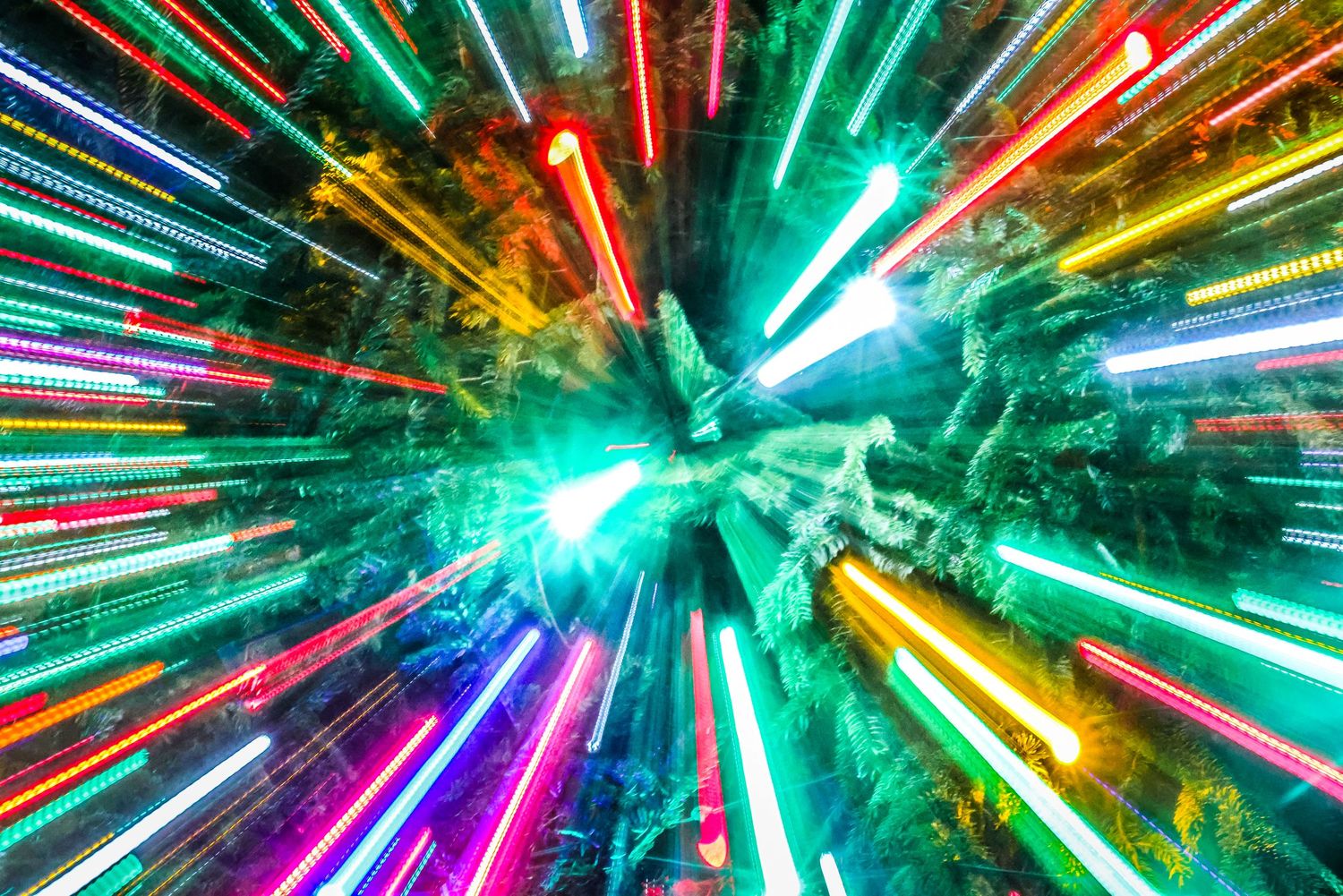 Colorful streaks of neon light radiate outward in a high-speed tunnel effect against a dark background.