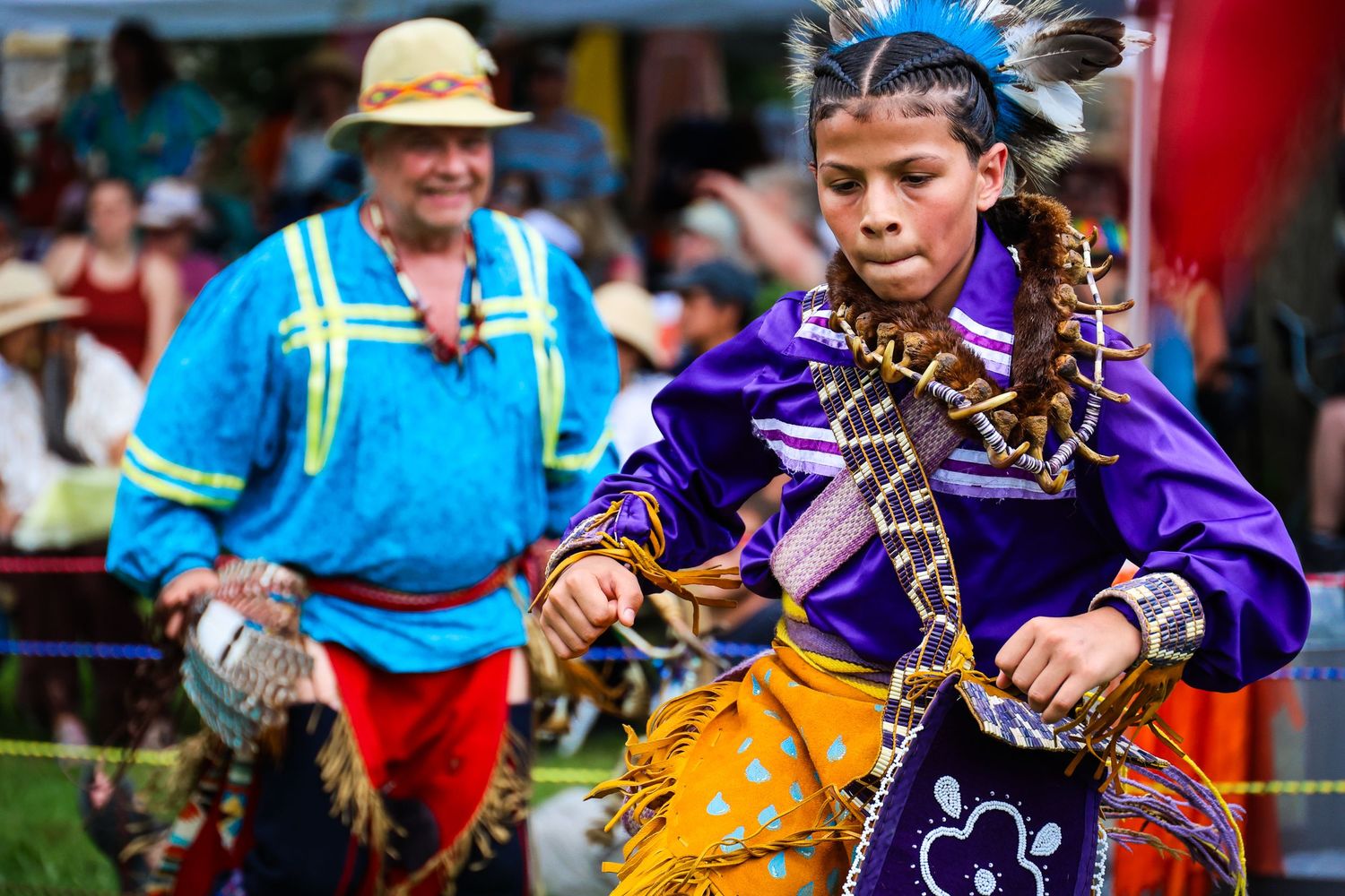 Performers in colorful traditional costumes dance and twirl during a lively folk festival celebration.
