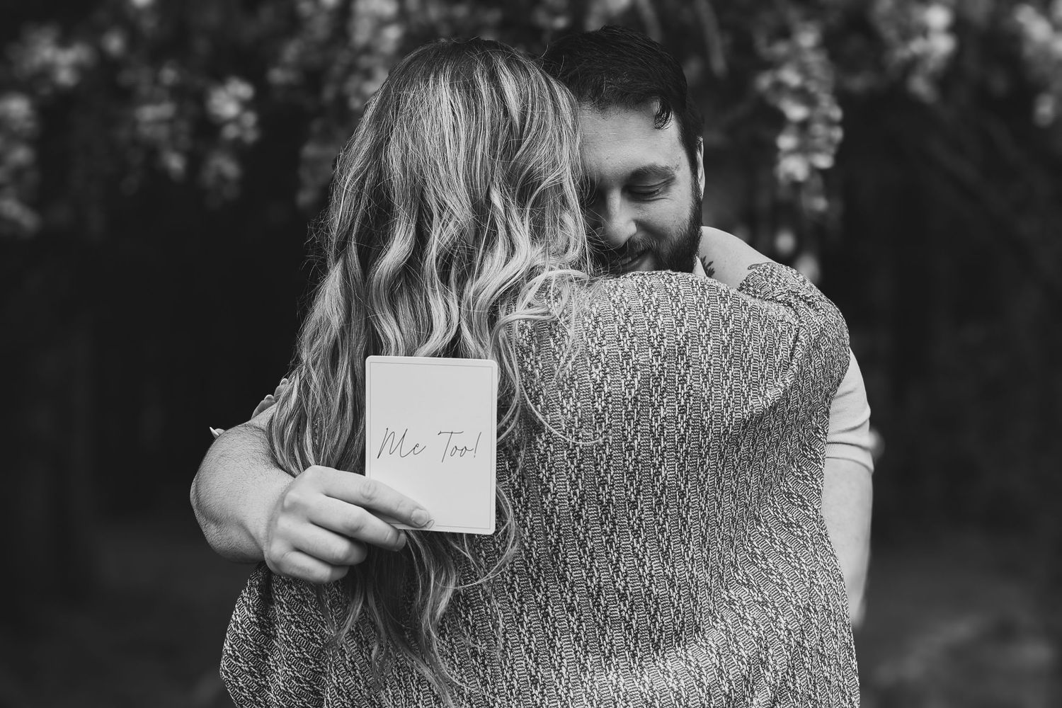 A series of black and white photos showing a couple embracing while holding handwritten notes outdoors.