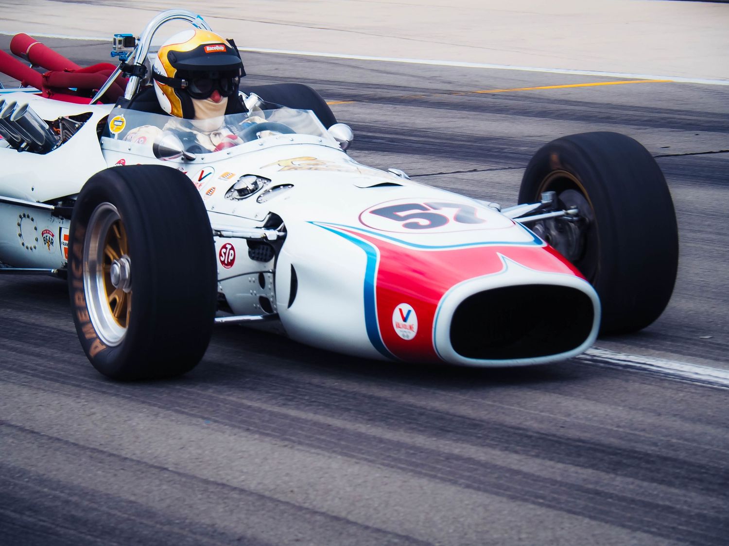 Vintage Formula 1 race cars speed through a curve on a racetrack during a historic racing competition.