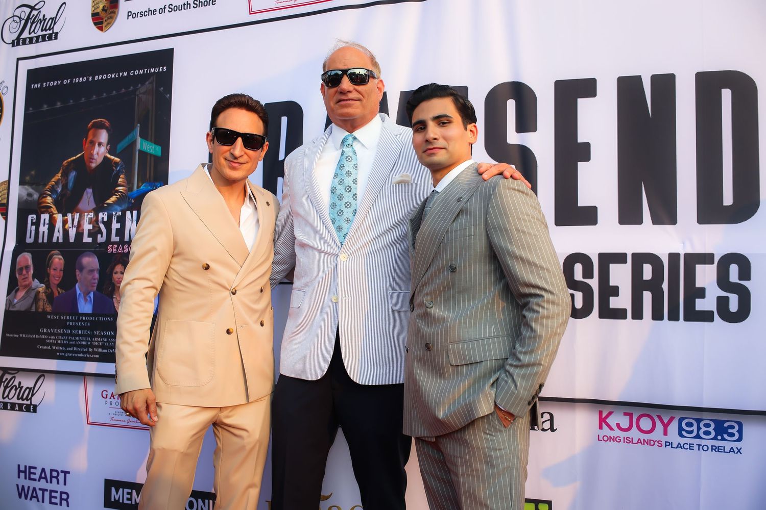 A group of men in suits and formal attire stand together at what appears to be a media or entertainment event.