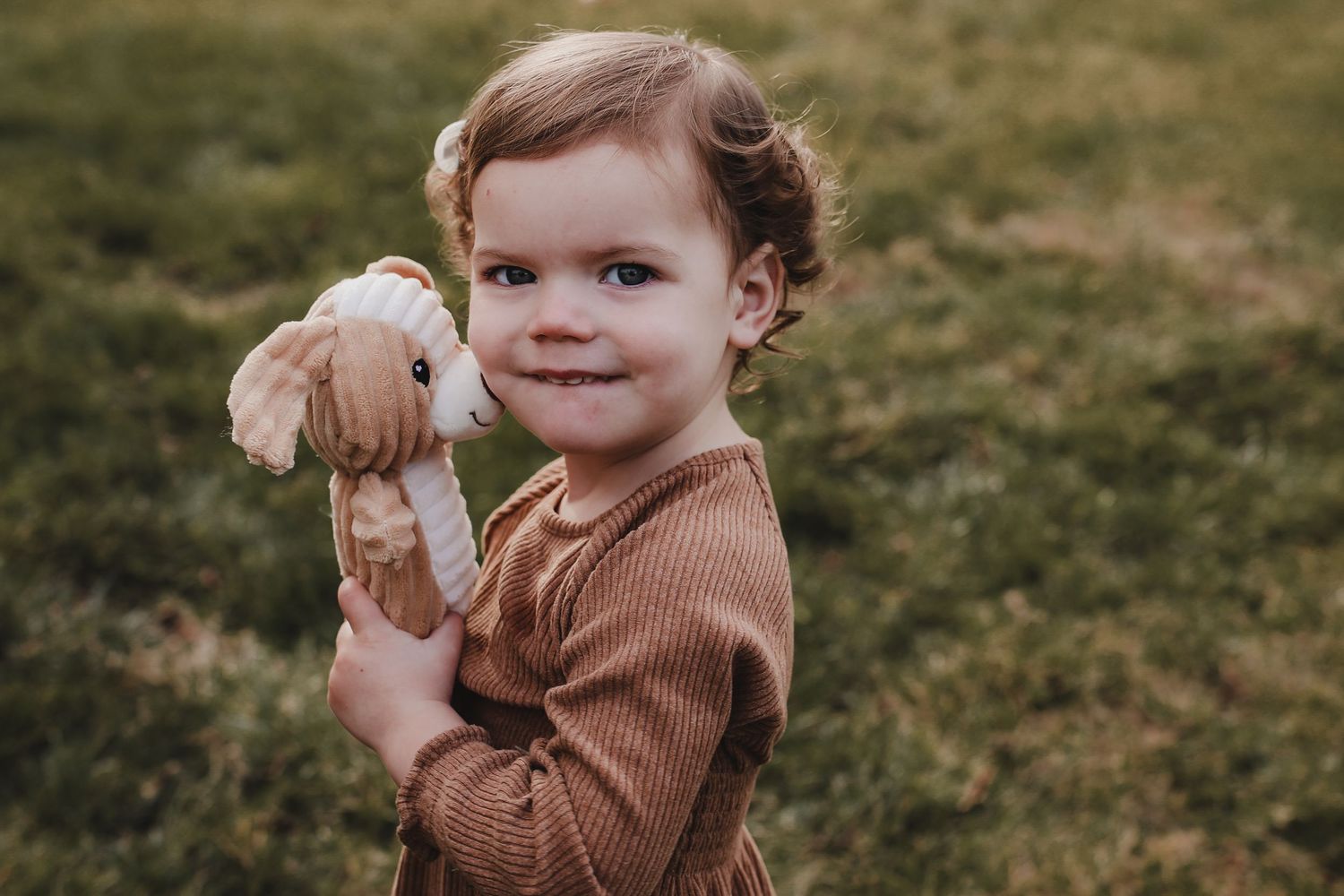 A sequence of seven photos showing a small child in a brown sweater playing outdoors in the grass.