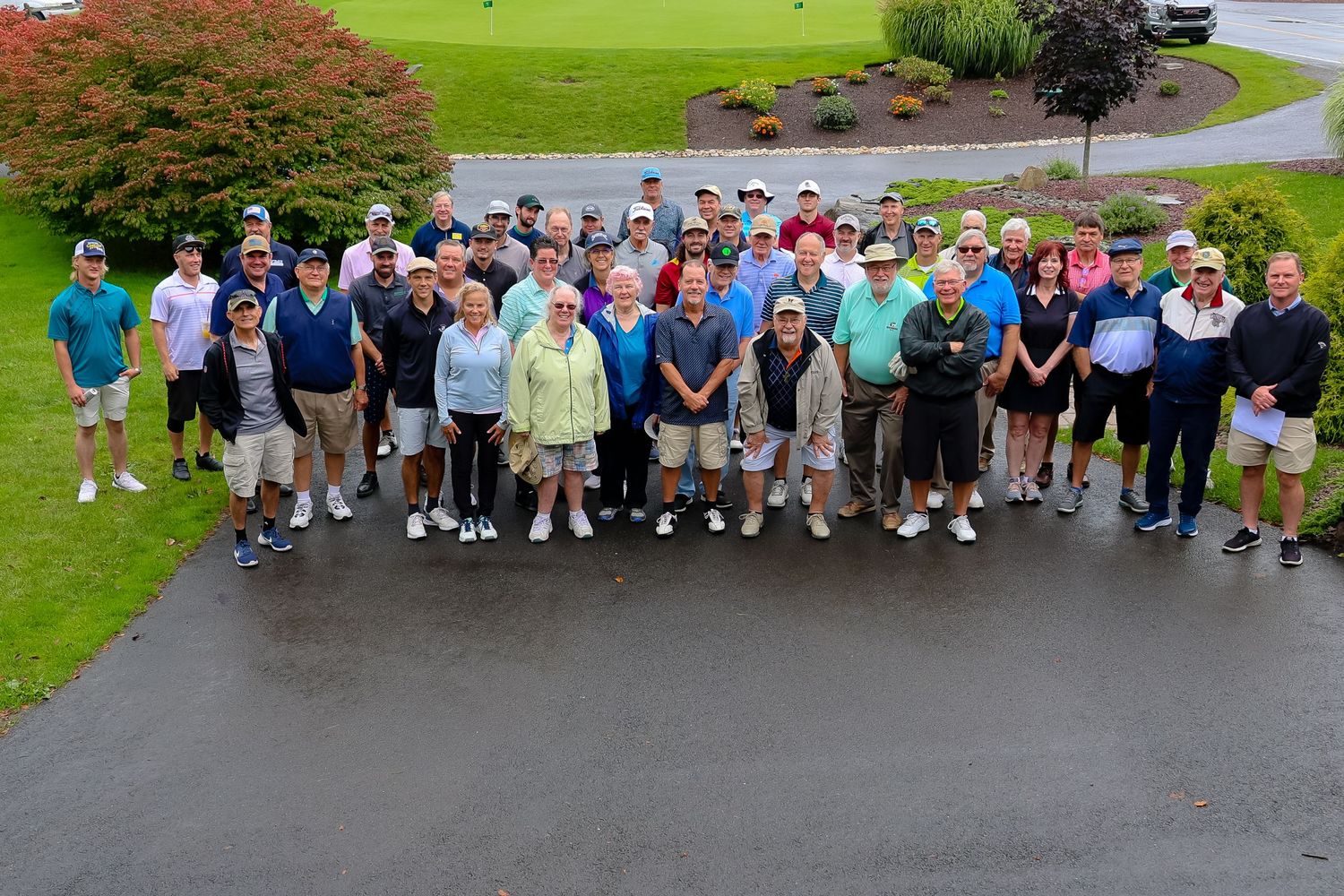 Large group of golfers gathered on a green course for a tournament or event on an overcast day.