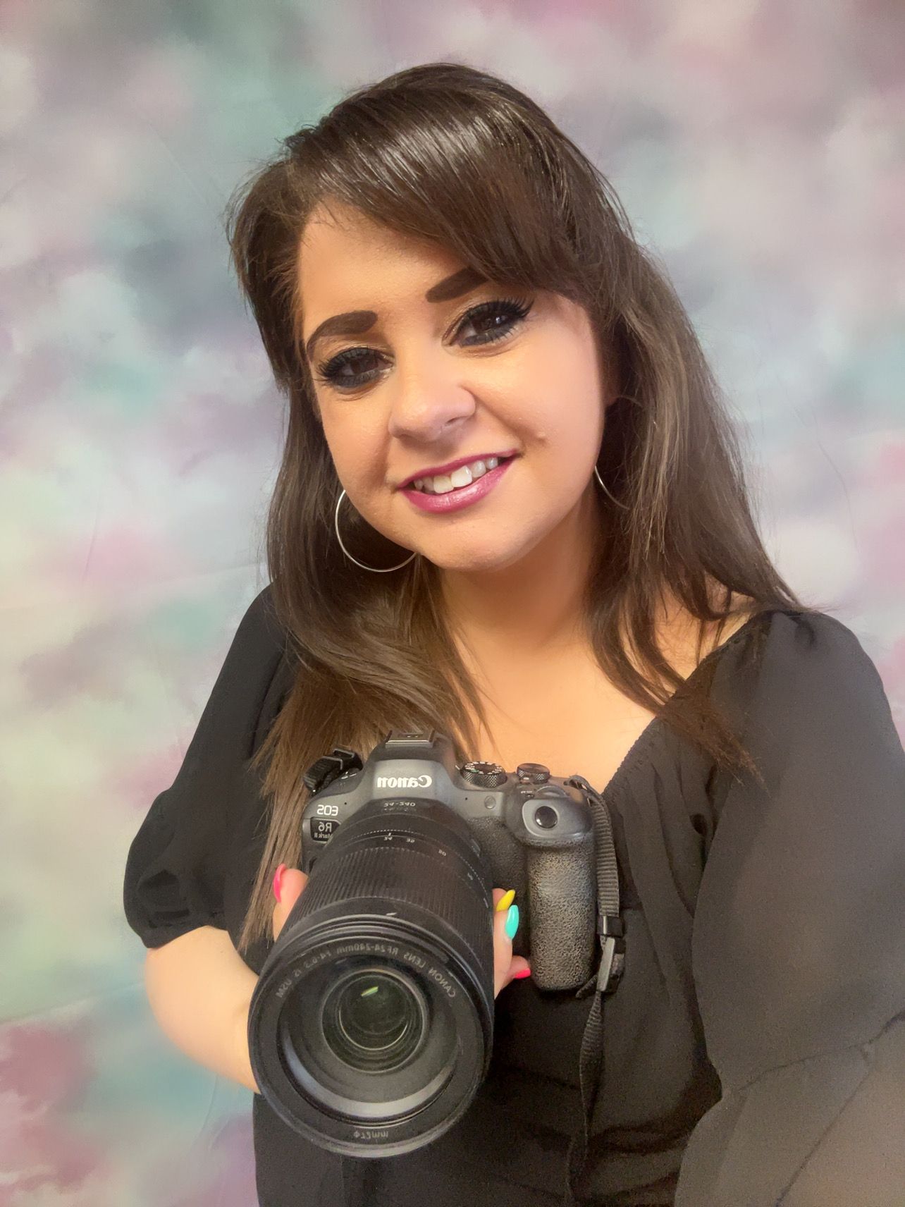 Professional photographer holding DSLR camera against colorful bokeh background.