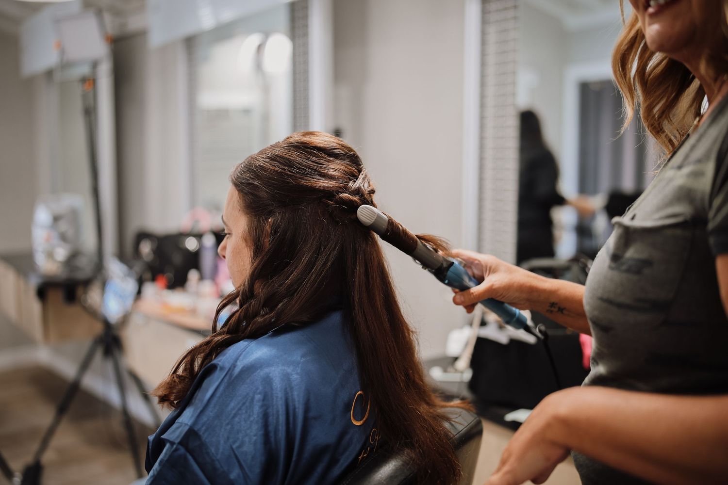Hairstylist working on client's hair in modern salon while using professional styling tools and products.