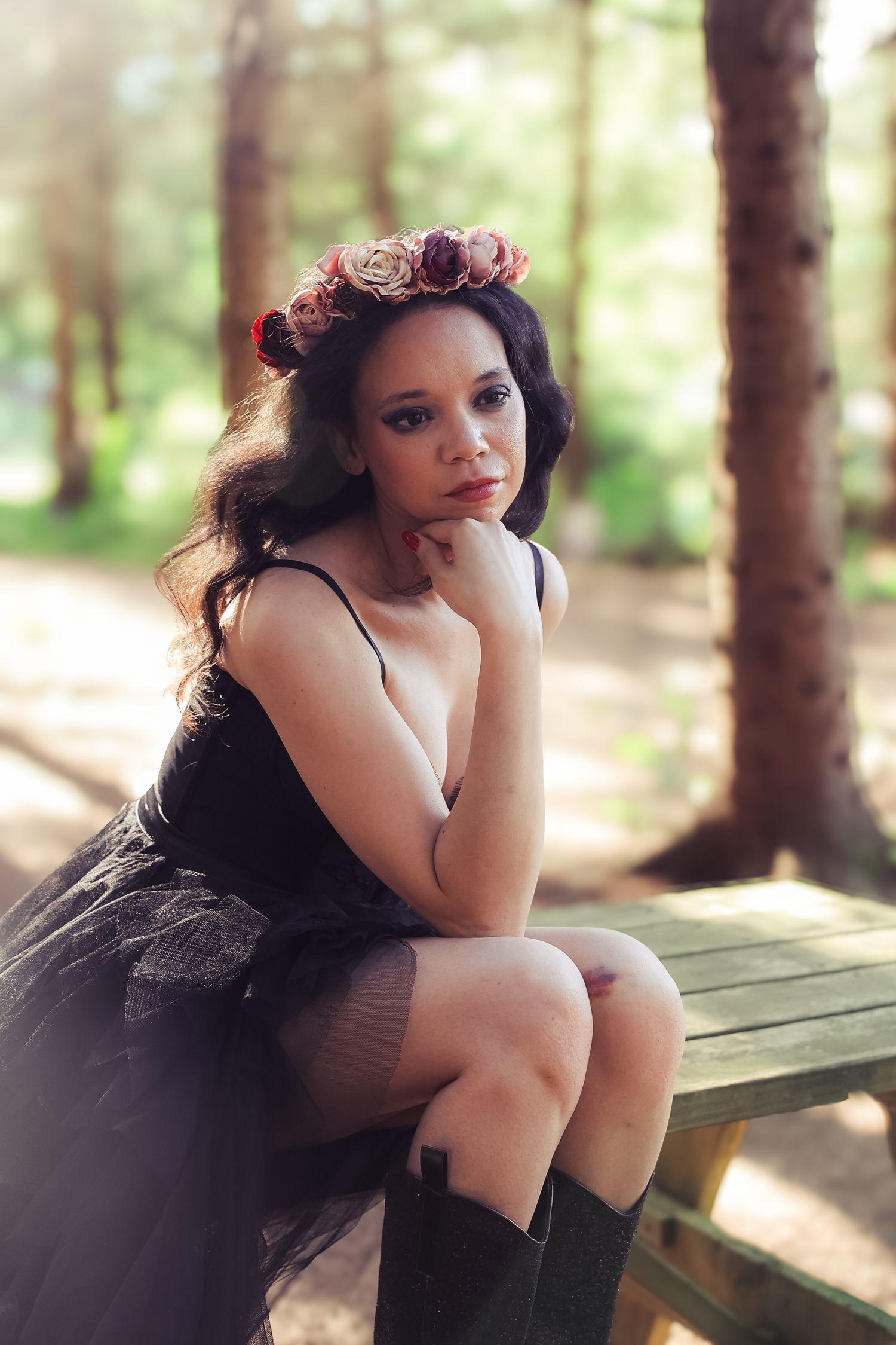 Artistic forest portrait session features ethereal styling with dark tulle dress and floral crown in dappled sunlight.