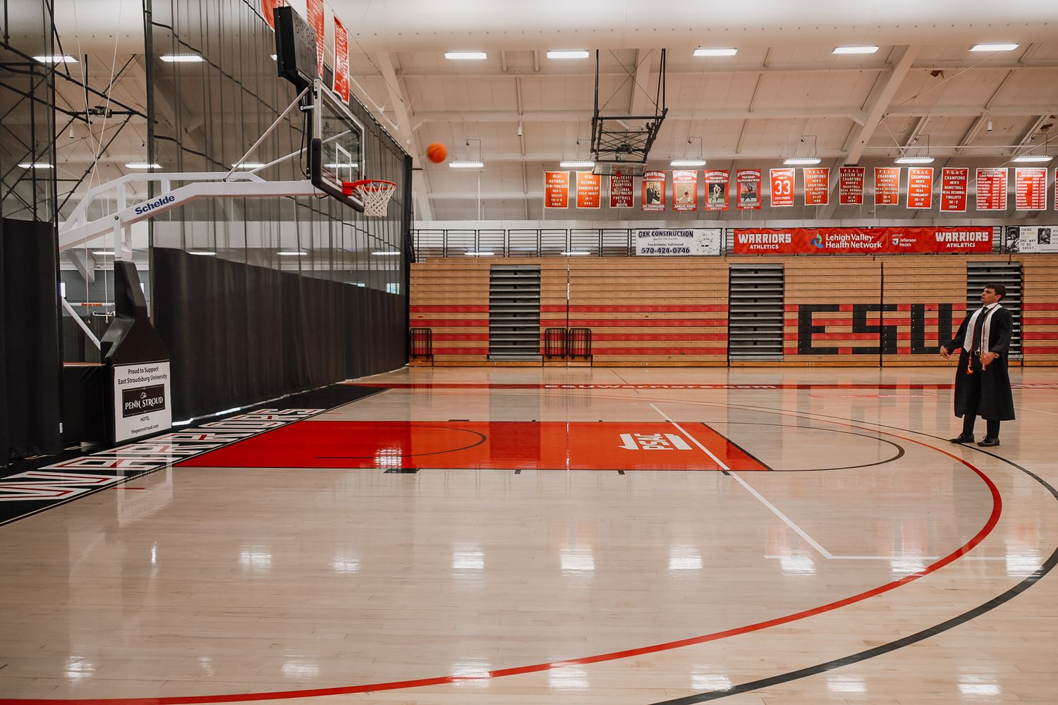 Empty CSU basketball gymnasium with red and white hardwood court, bleachers, and banners hanging from the ceiling.