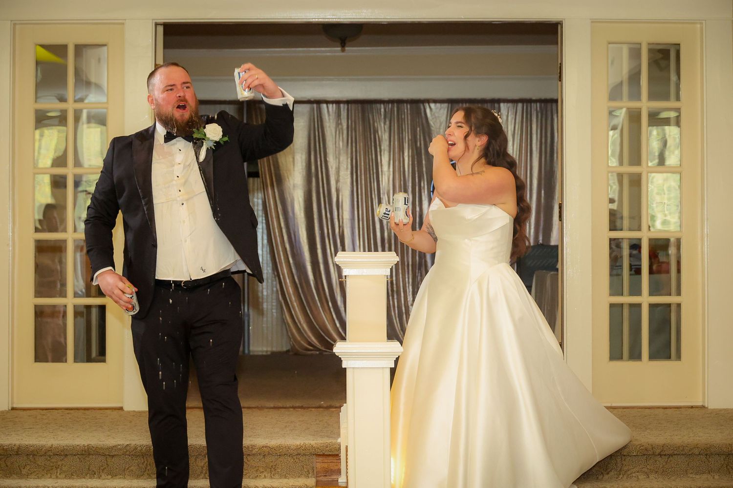 Bride and groom laughing during champagne toast at elegant wedding reception venue.